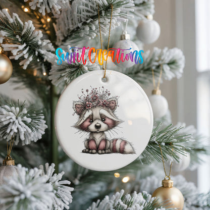 woodland raccoon wearing a pink winter bow ceramic Christmas ornament hanging on a frosted Christmas tree