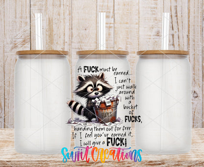 A F*ck Must Be Earned Raccoon UV DTF transfer applied to a clear glass can set from Swiit Creations