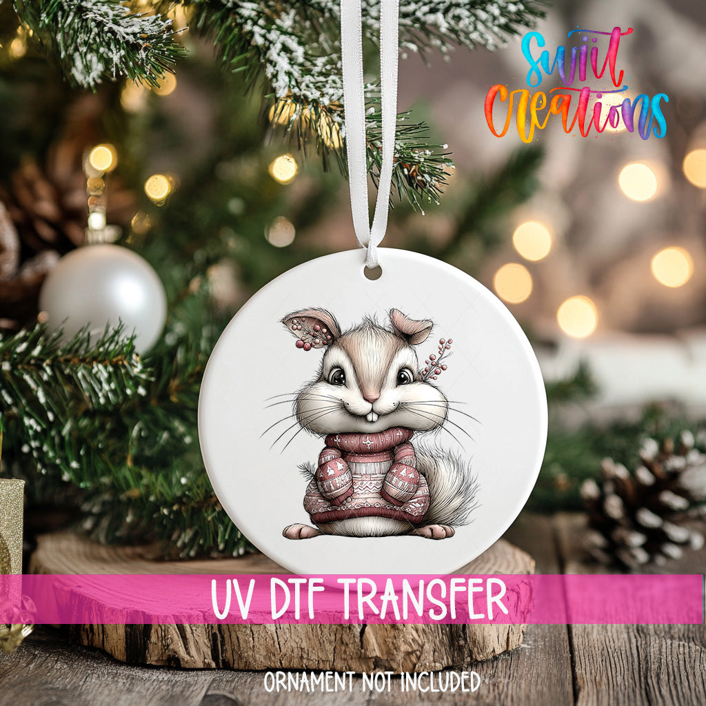 A white ceramic ornament featuring a cartoon rabbit wearing a sweater, hanging on a Christmas tree.