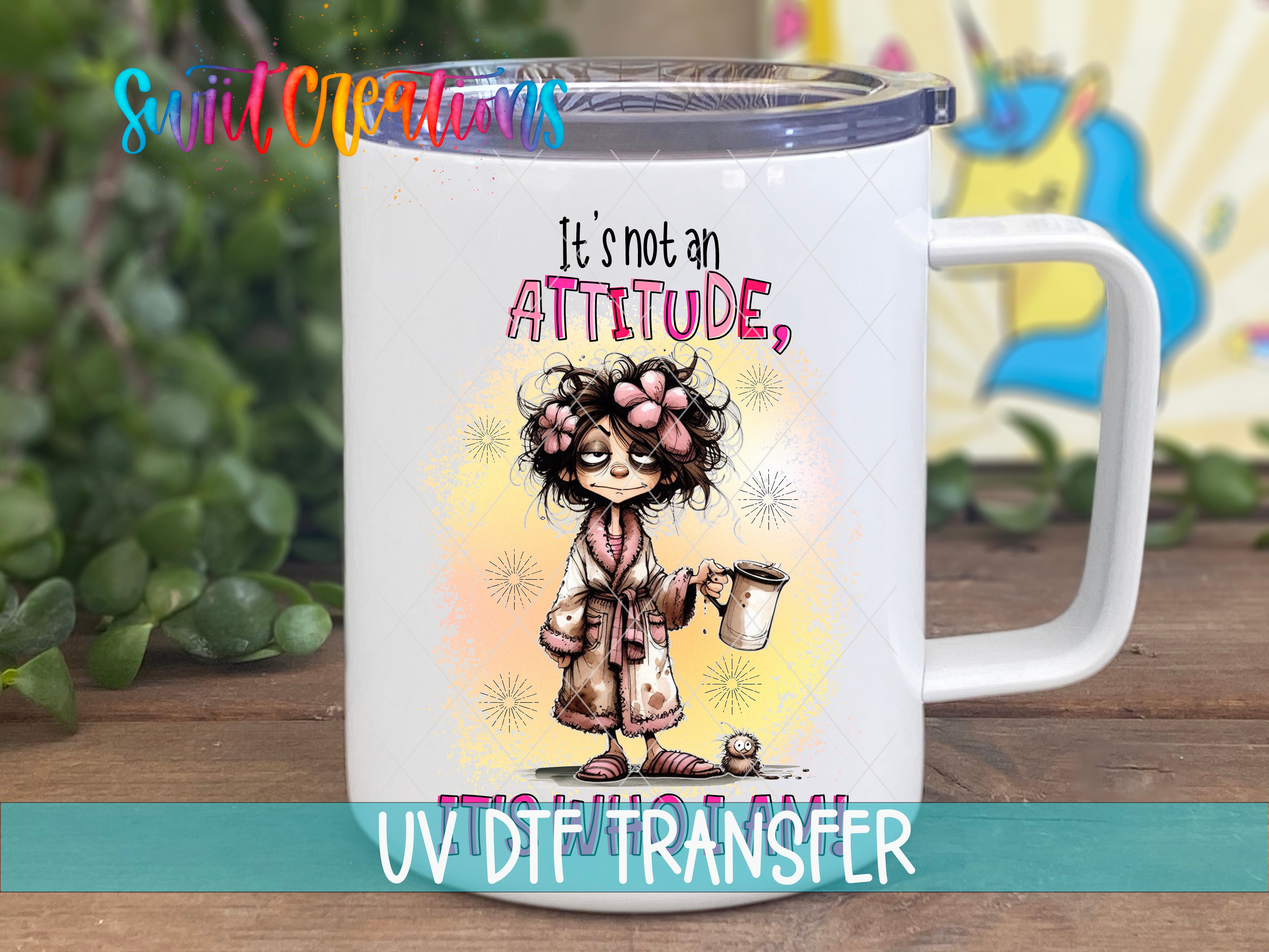 A white mug with a colorful illustration of a woman with curly hair and a flower in her hair, along with the text "It's not an ATTITUDE, UV DTHTRANSFER".