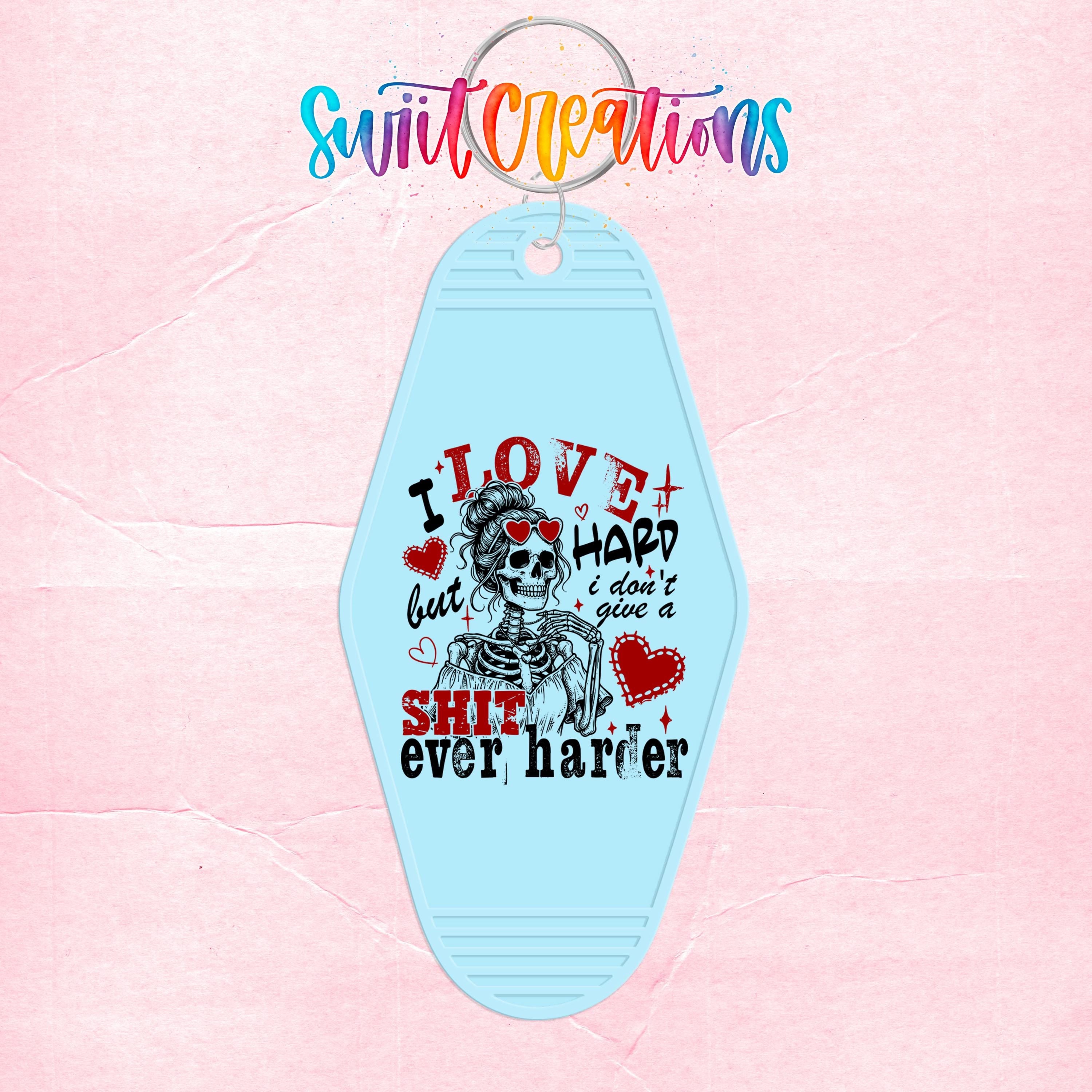 A keychain with a skeleton design and text that says "I LOVE HARD I DON'T GIVE A SHIT EVER HARDER".