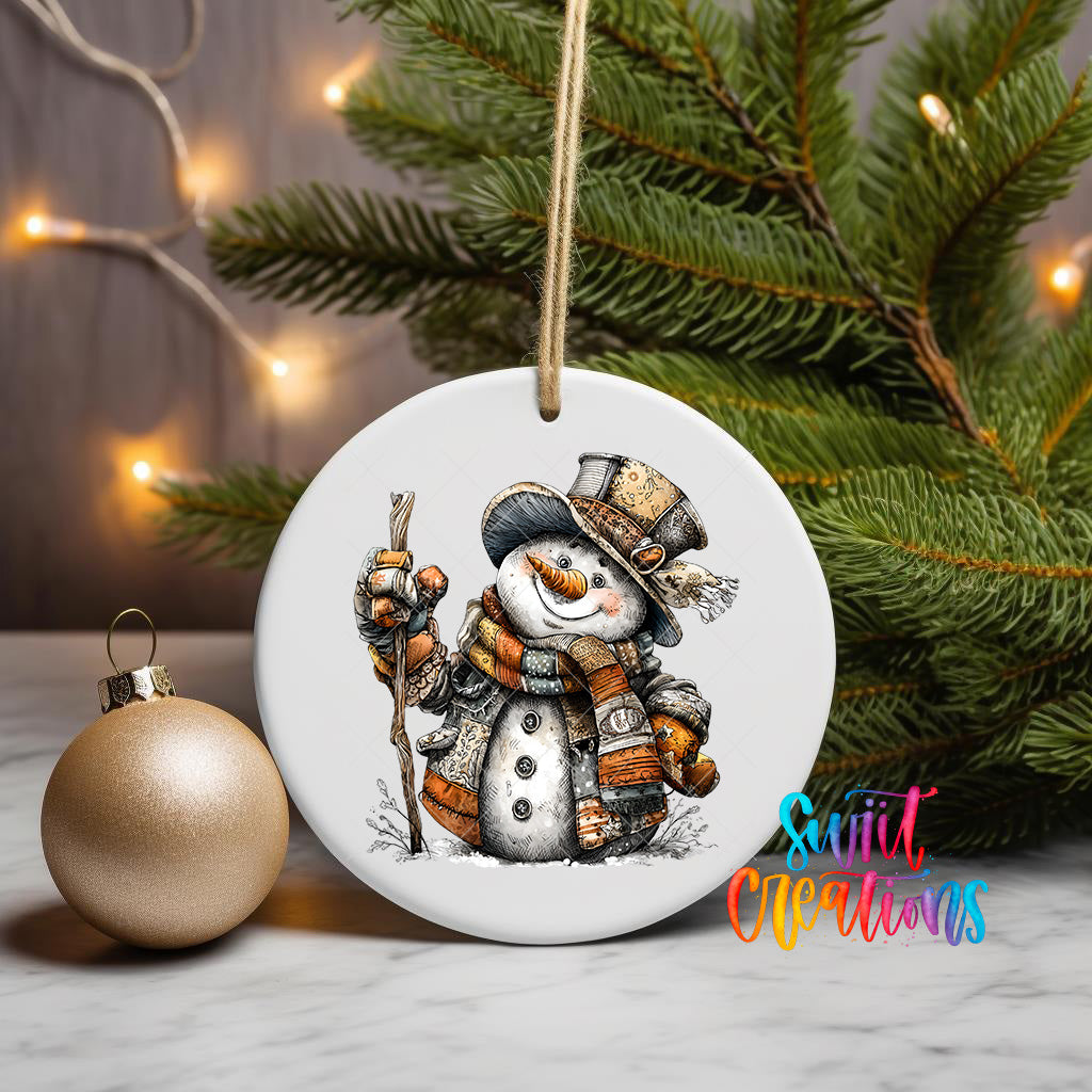 A white ceramic ornament featuring a snowman is displayed on a table, with a gold ornament and a Christmas tree in the background.