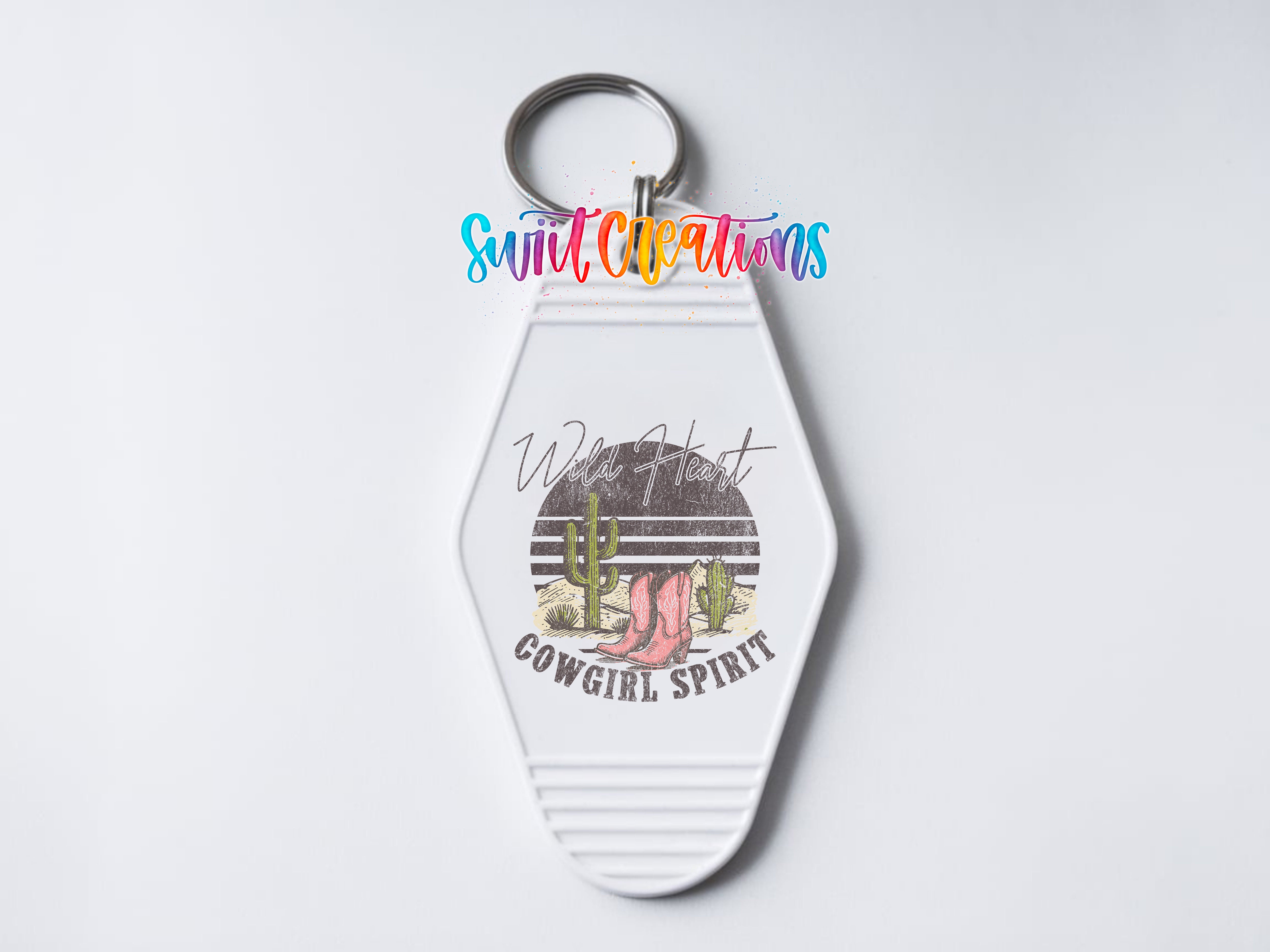 A keychain with a graphic design featuring a cactus, a cowboy boot, and the text "Wild Hearts Cowgirl Spirit".
