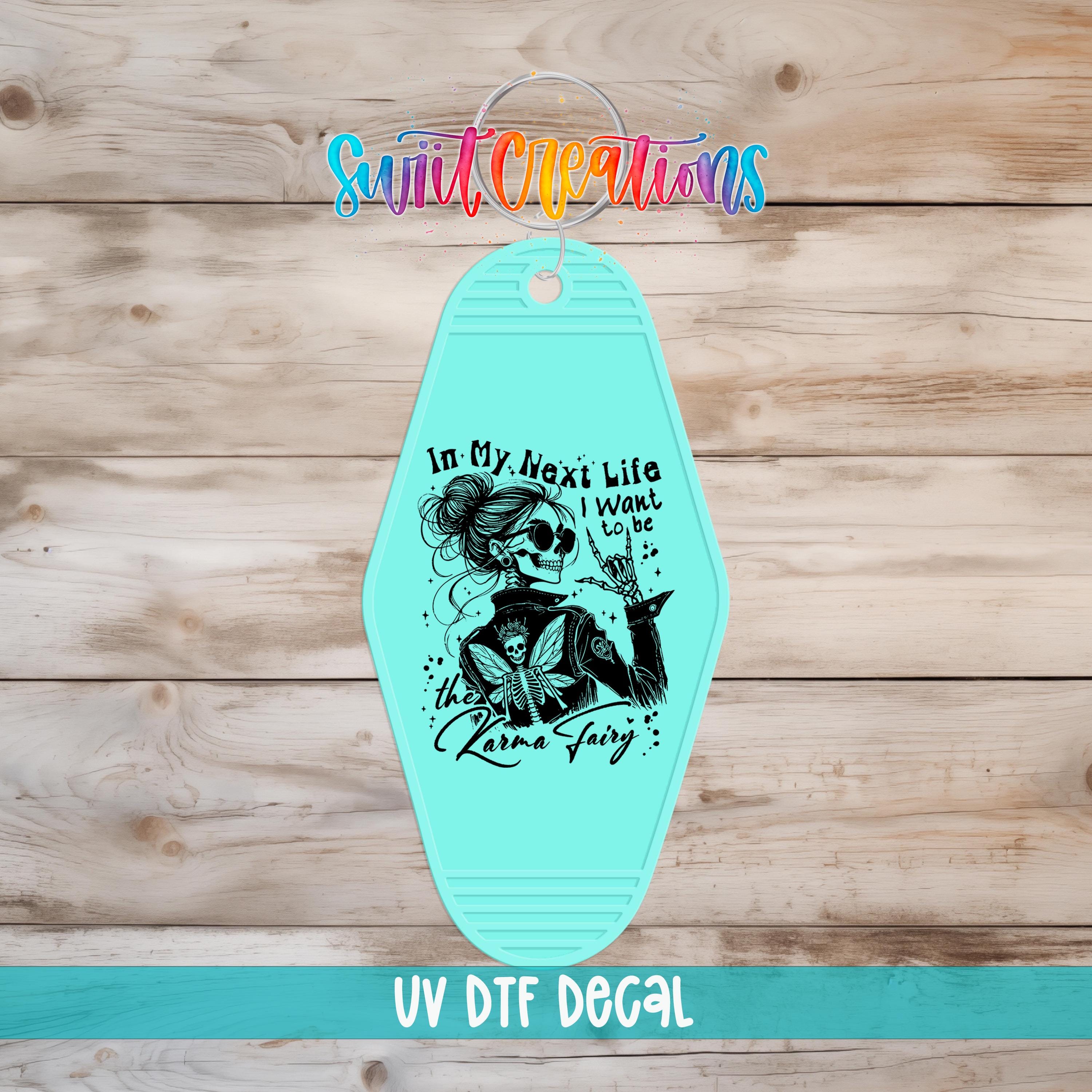 A turquoise keychain with a black and white illustration of a woman and text that says "In my next life I want to go to the karaoke fairy".