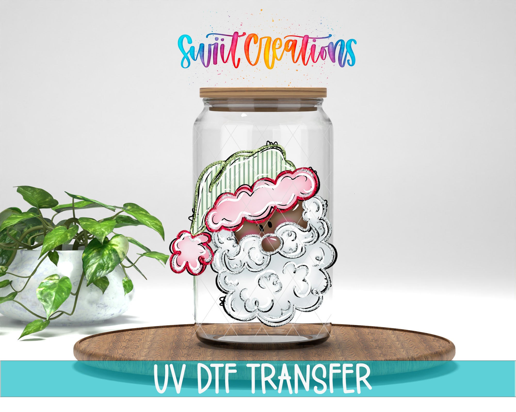 a glass jar with a Santa Claus drawing inside, placed on a wooden surface. There is a potted plant in the background, and the image includes text that says "Swit Creations UV Dtf Transfer".