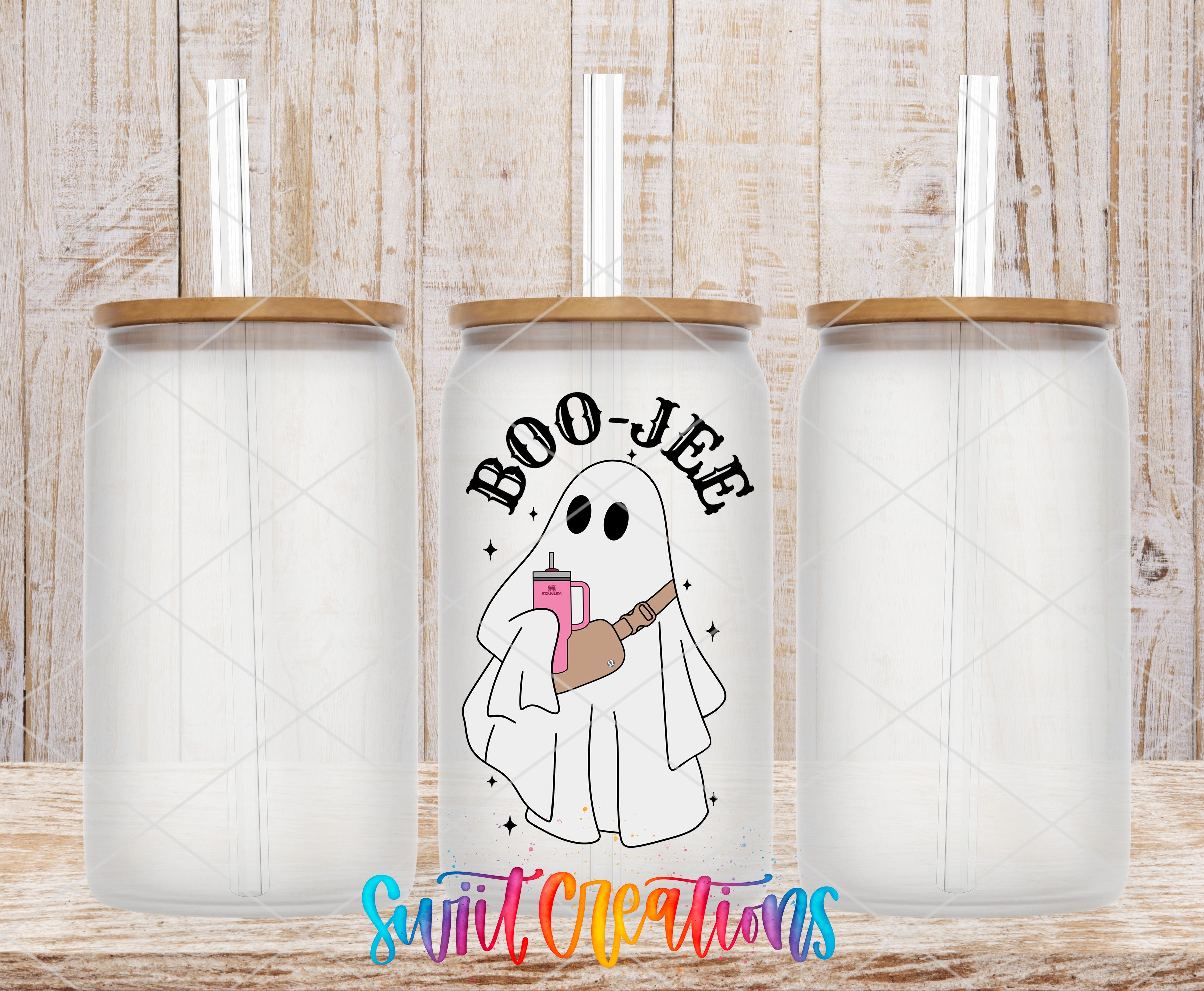 three clear glass tumblers with a unique design on the center one. The design includes a ghost holding a pink object and the text "BOO-JEE" written above it.