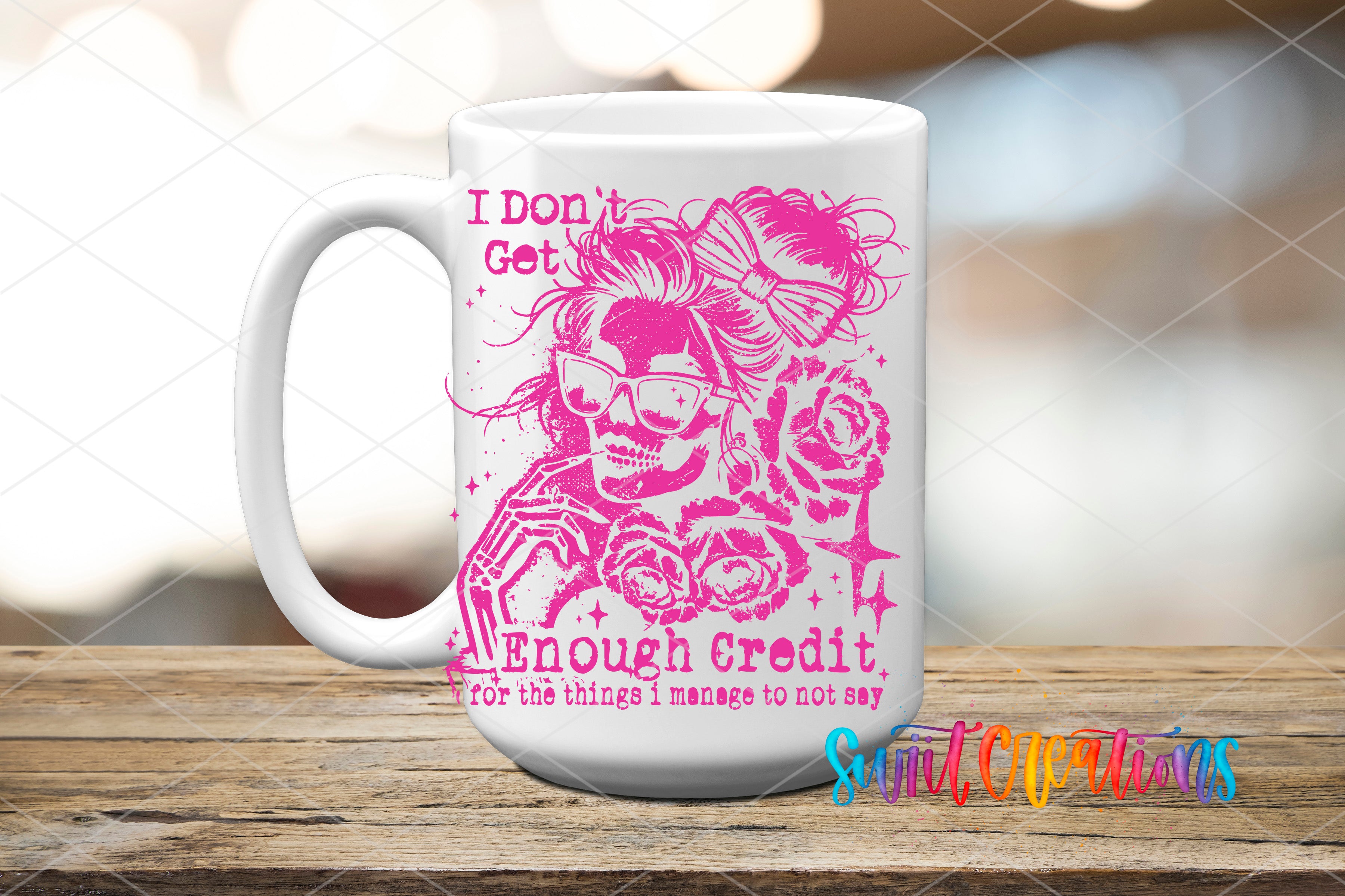 A white mug with a pink and purple design featuring a skull wearing sunglasses and holding a rose. The mug has text that reads "I Don't Get Enough Credit for the things I manage to not say" and "Suitcase Creations".