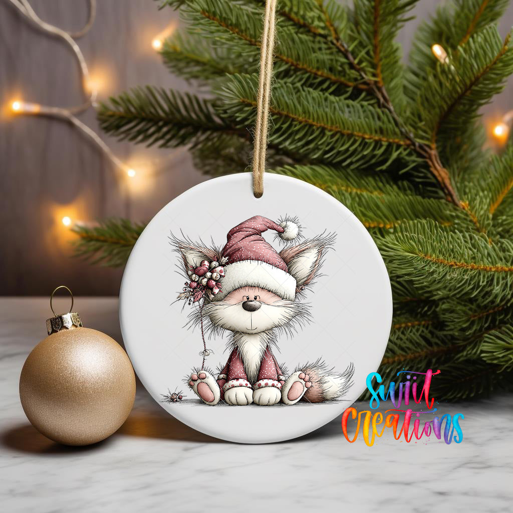 A ceramic ornament featuring a cartoon cat wearing a Santa hat, sitting on a branch with a Christmas tree in the background.