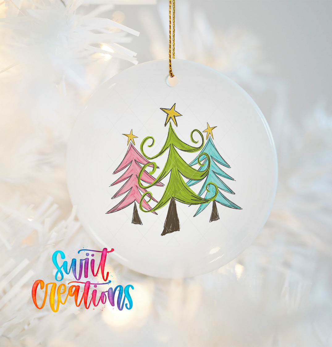 A white Christmas ornament with a drawing of three stylized Christmas trees in different colors, including pink, green, and blue, hanging from a string.
