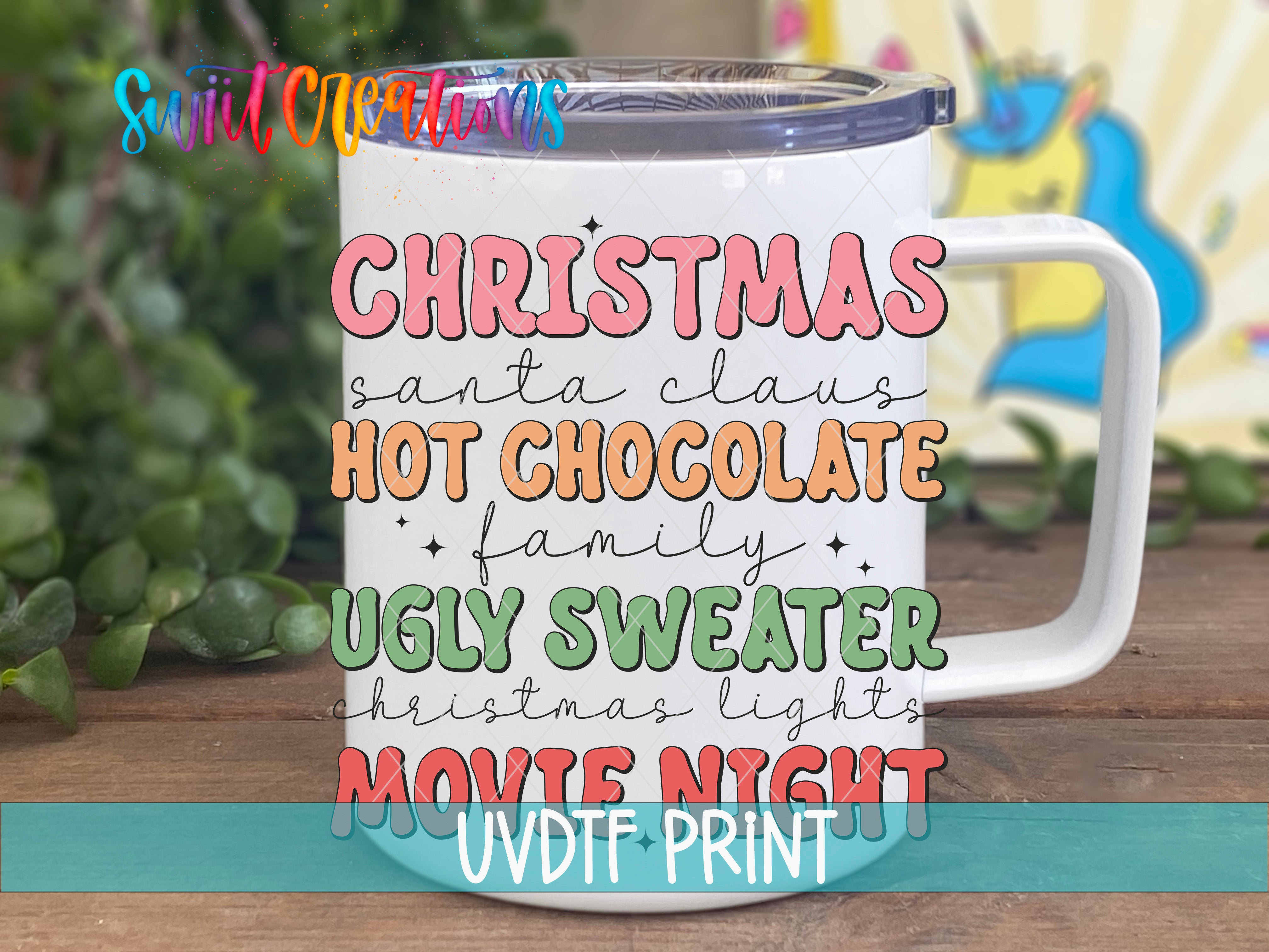 A white mug with colorful text printed on it, placed on a wooden surface with greenery in the background.