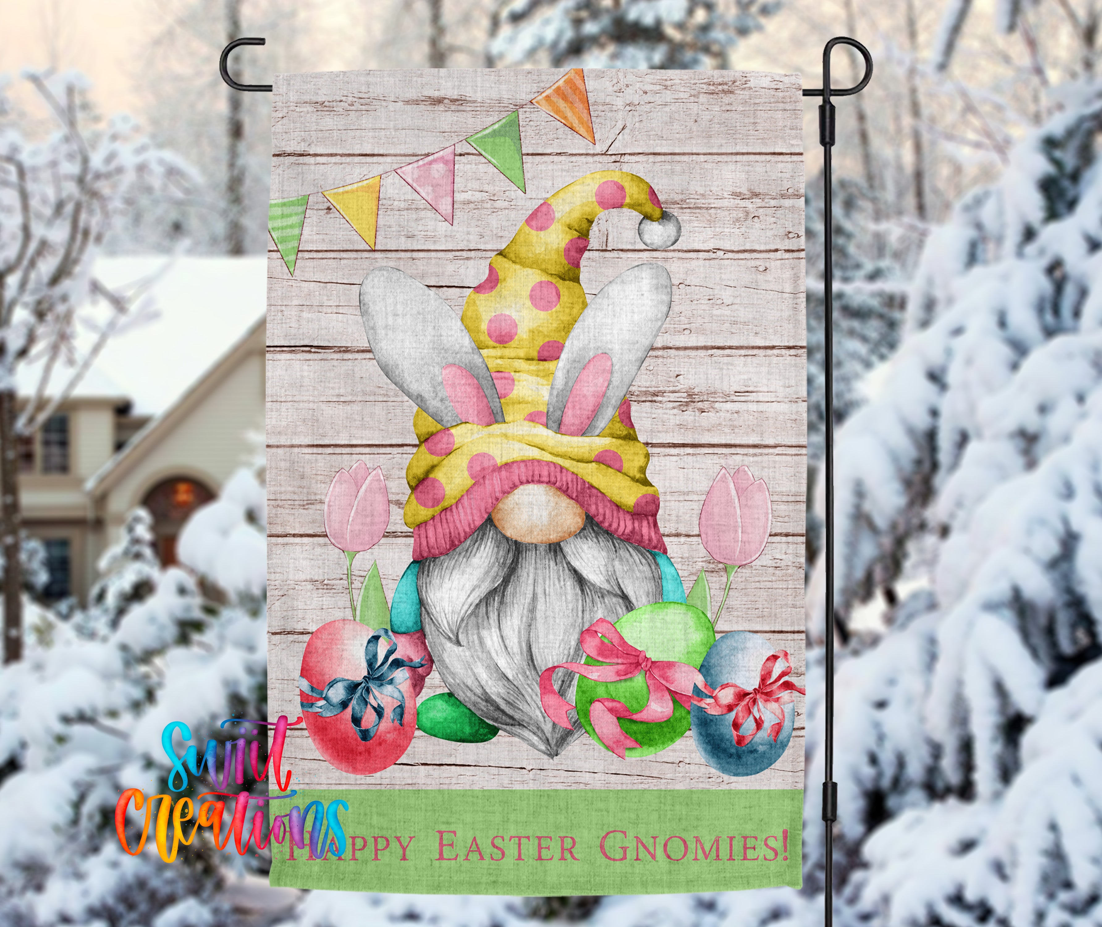 A colorful Easter-themed garden gnome decoration is displayed outdoors, with a snowy background and a house visible in the distance.