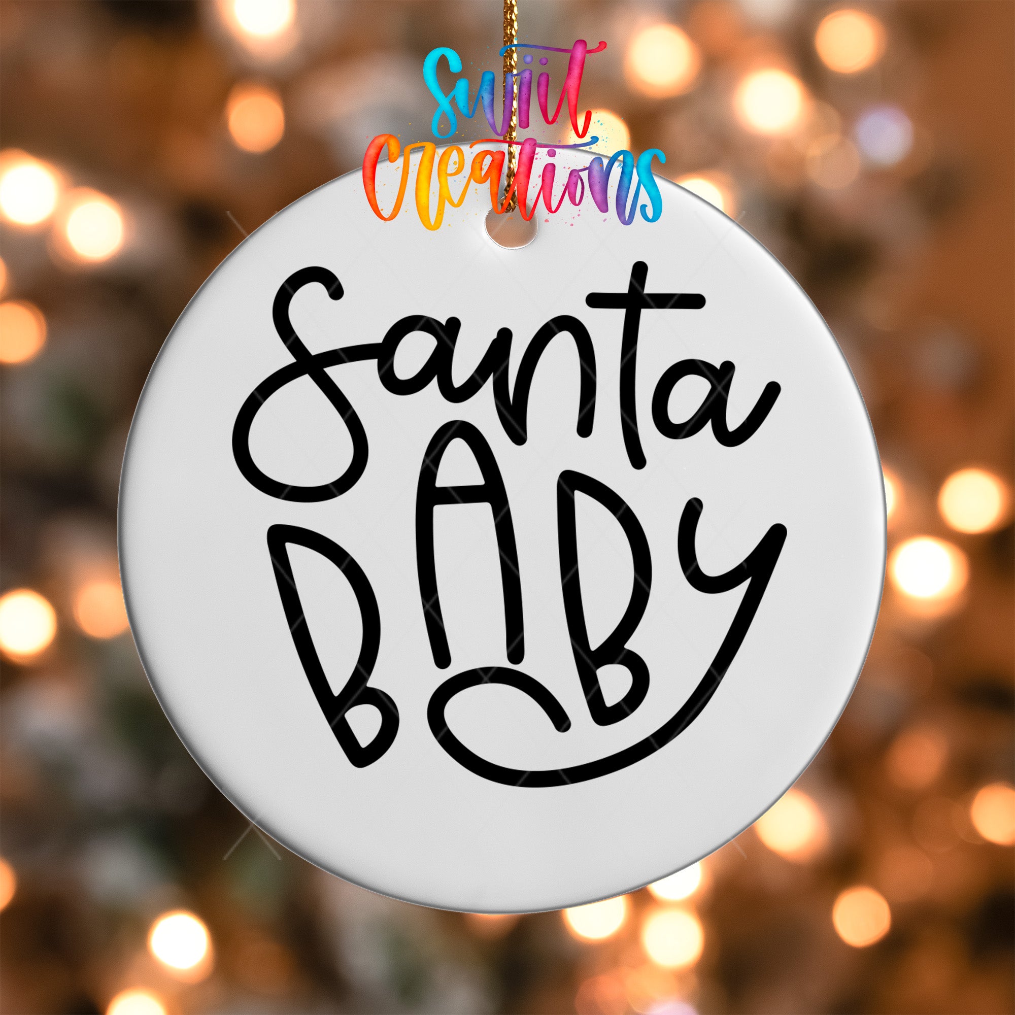 A white ornament with the text "Santa Baby" written on it, hanging against a background of colorful lights.