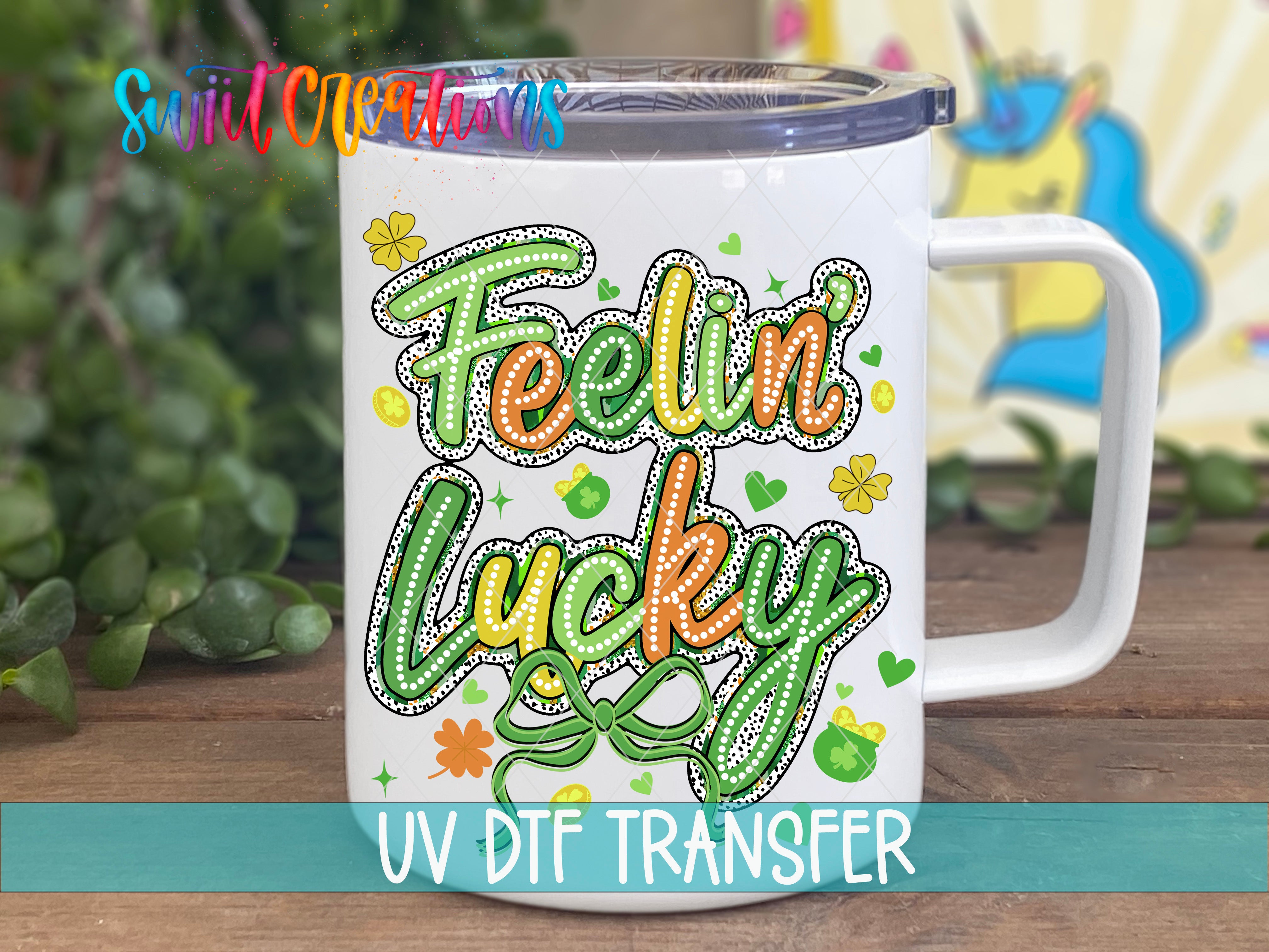 A white mug with a colorful design featuring the text "Feelin Lucky" and various decorative elements such as hearts, flowers, and leaves.