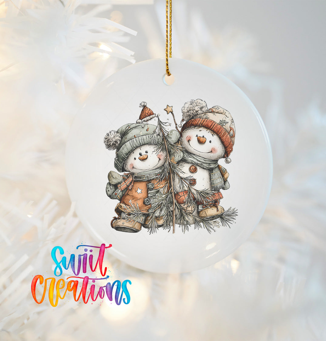 A white ornament with a snowman and pine tree design hangs against a white background.