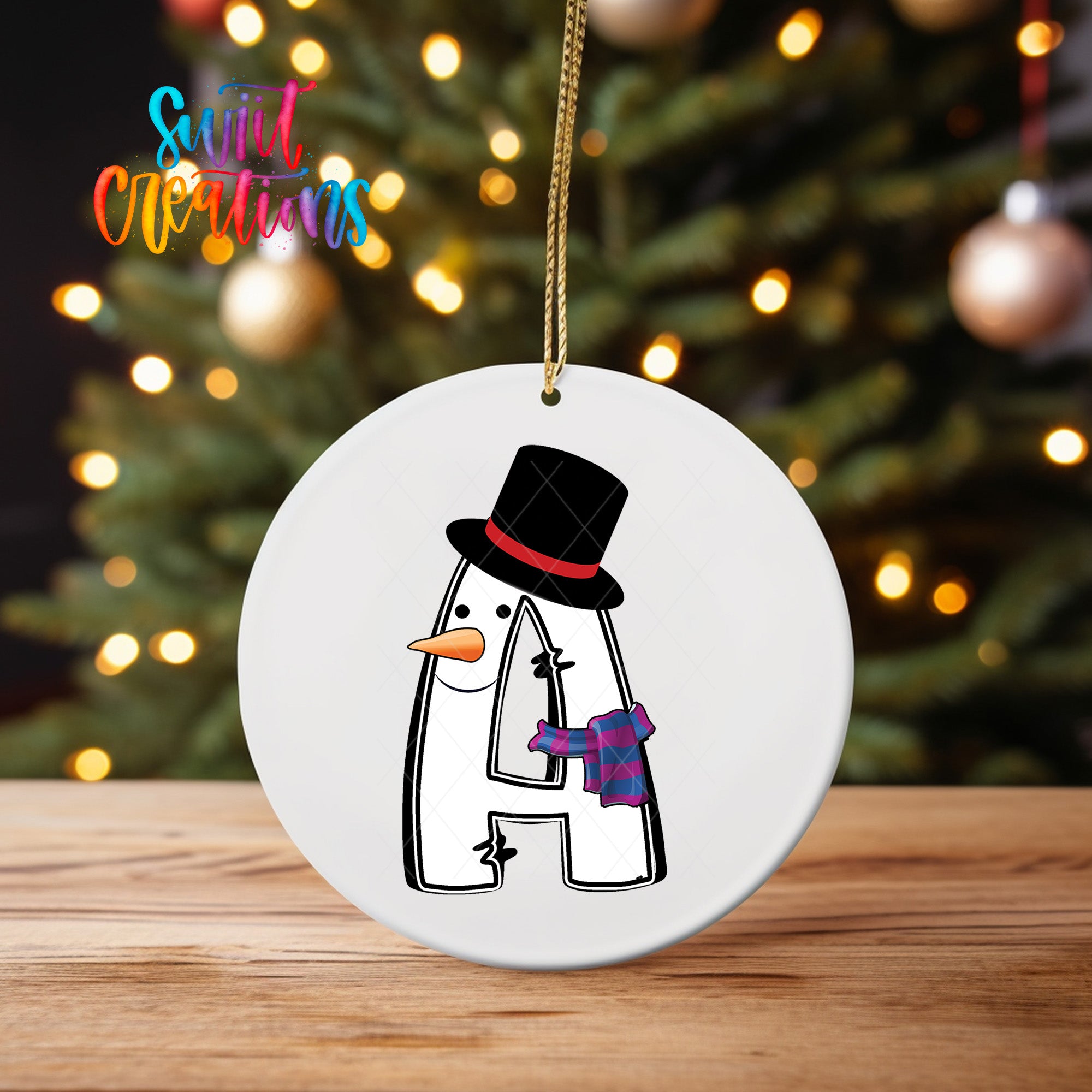 A white ornament with a snowman design and a black top hat is hanging on a string.
