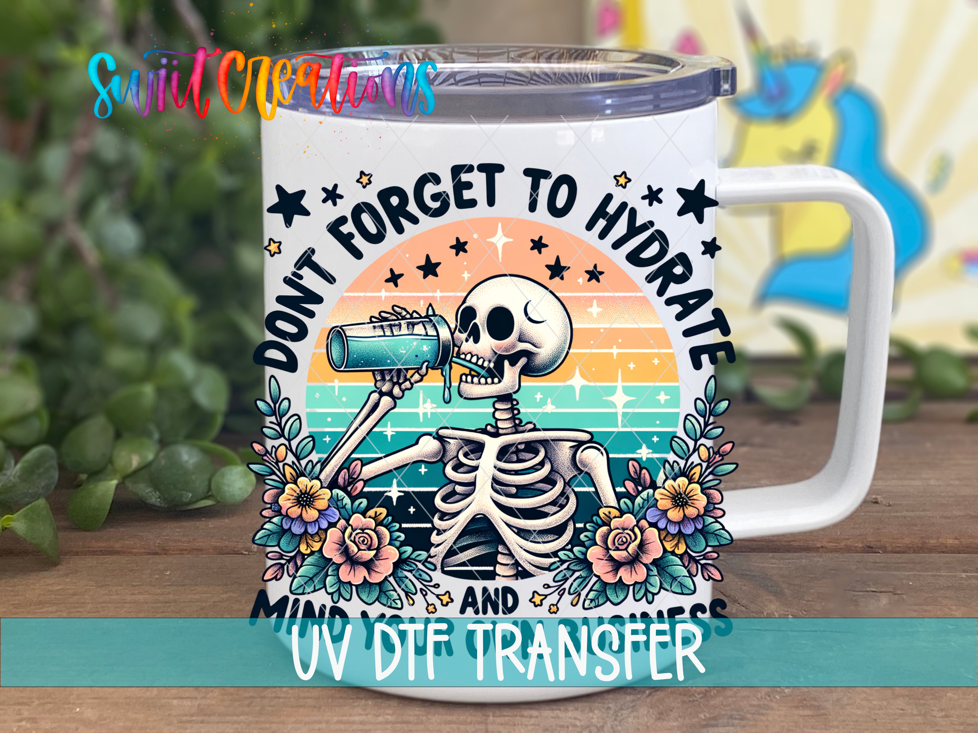 A mug with a skeleton drinking from a cup, surrounded by flowers and stars, with the text "Don't forget to hydrate" and "UV DFT Transfer" printed on it.