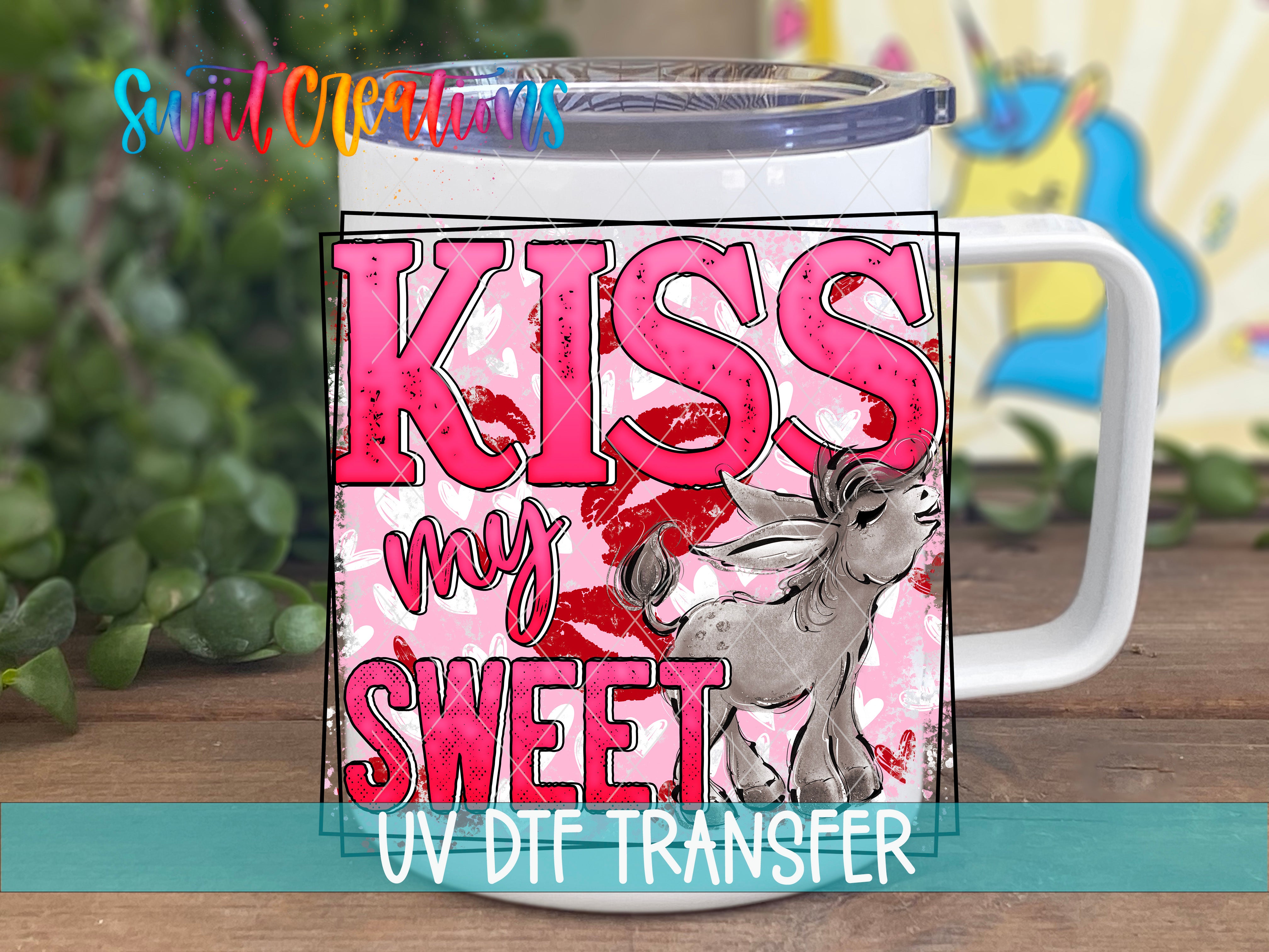 A white mug with a pink and red design featuring the text "KISS MY SWEET" and an illustration of a cartoon character.