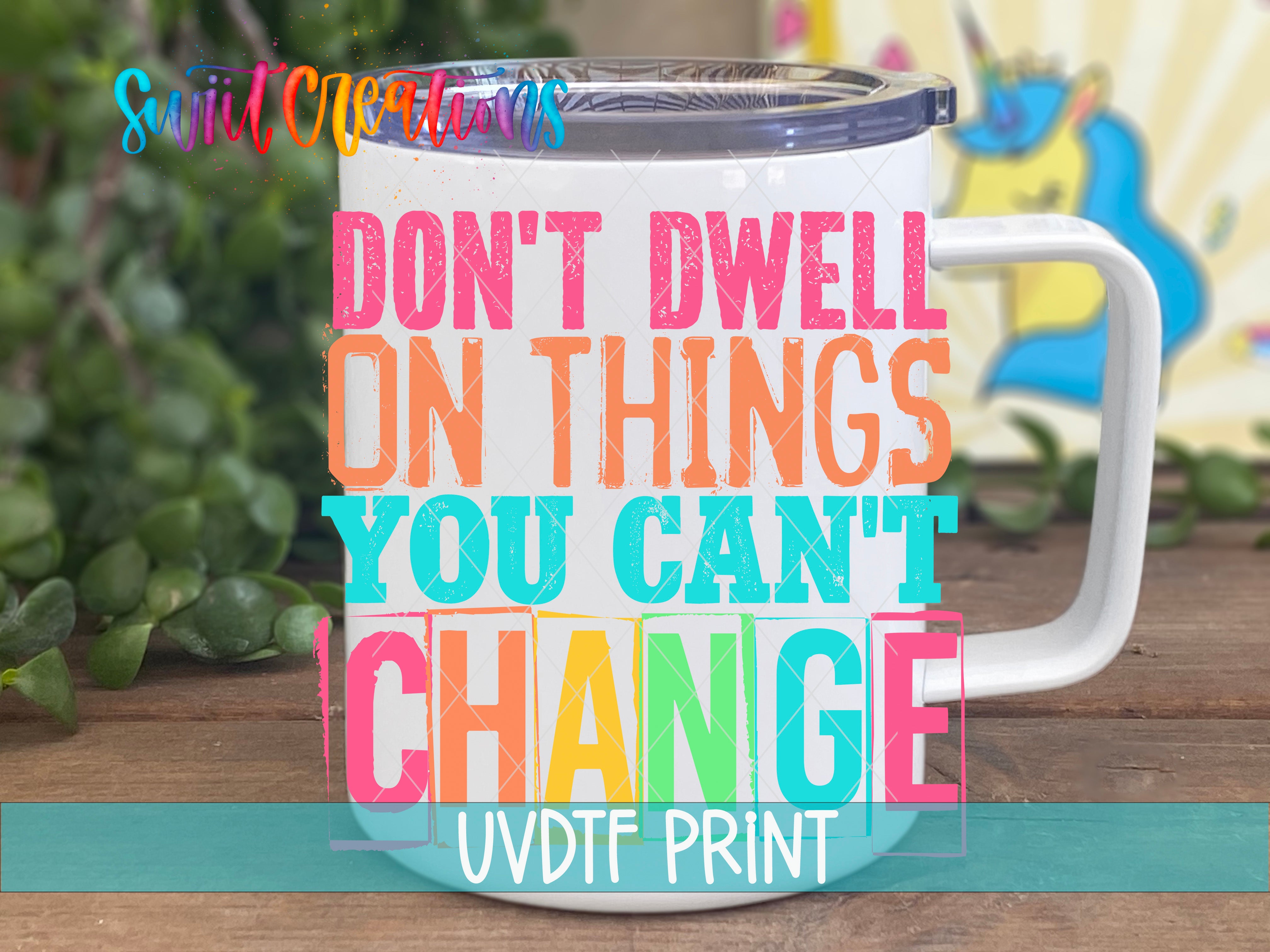 A white mug with colorful text on it, placed on a wooden surface.