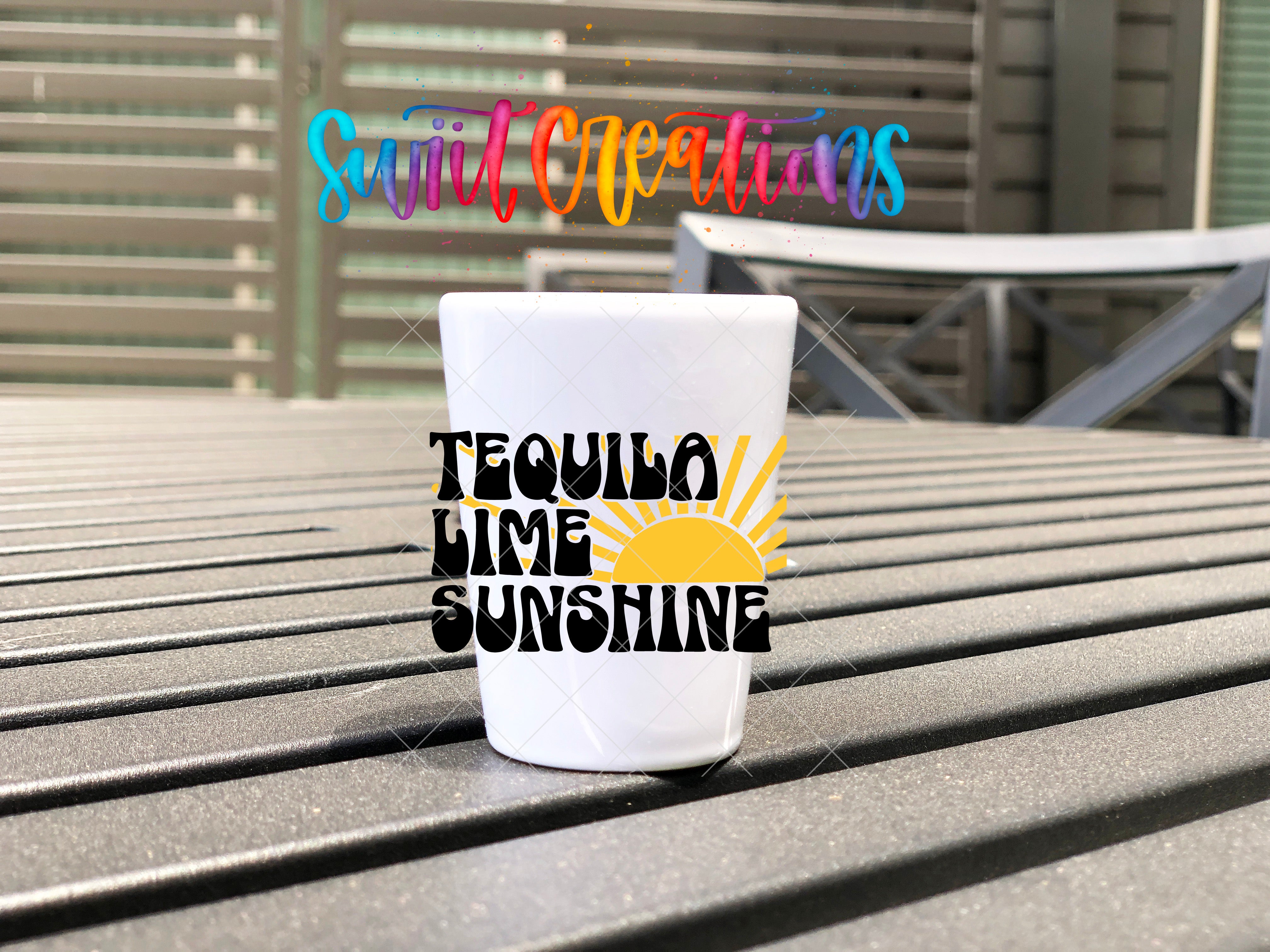 A white tequila lime sunshine shot cup sits on a wooden surface, with colorful text in the background that reads "SwitlCreations" and "Tequila Lime Sunshine".