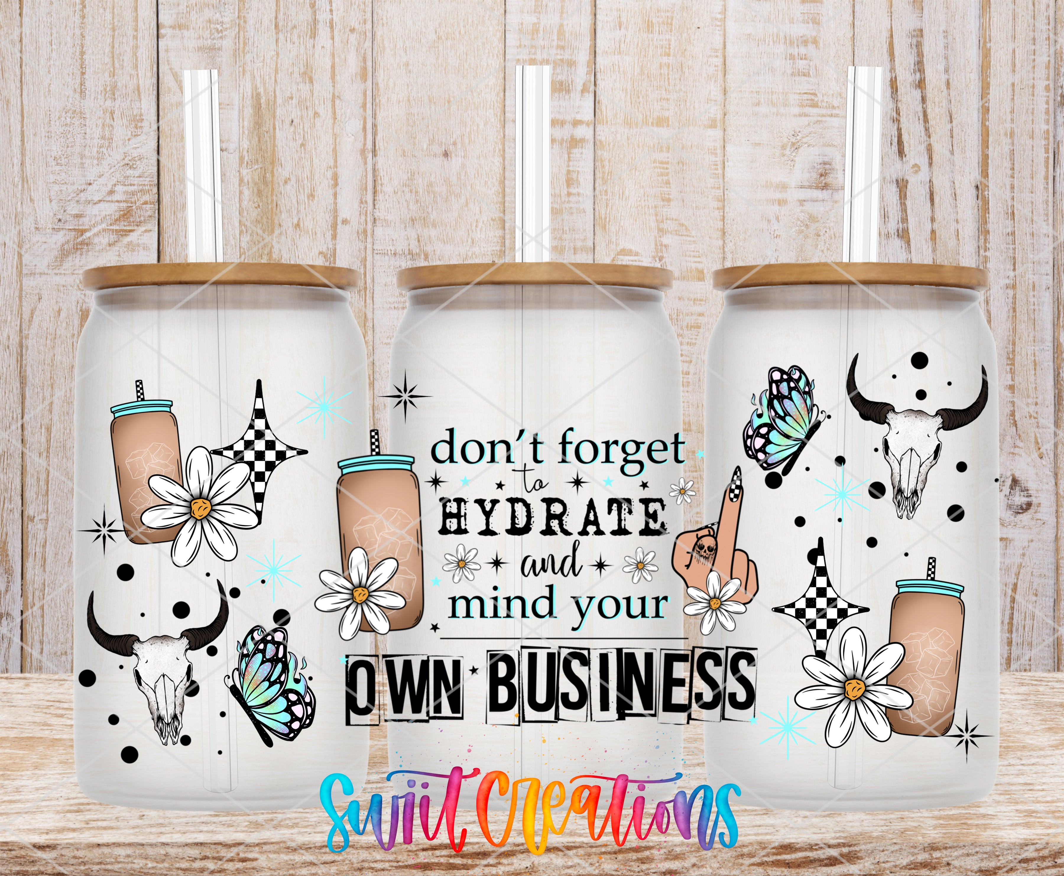 three glass tumblers with various designs and illustrations, including flowers, butterflies, and skulls. The text on the tumblers reads "don't forget to hydrate and mind your own business".