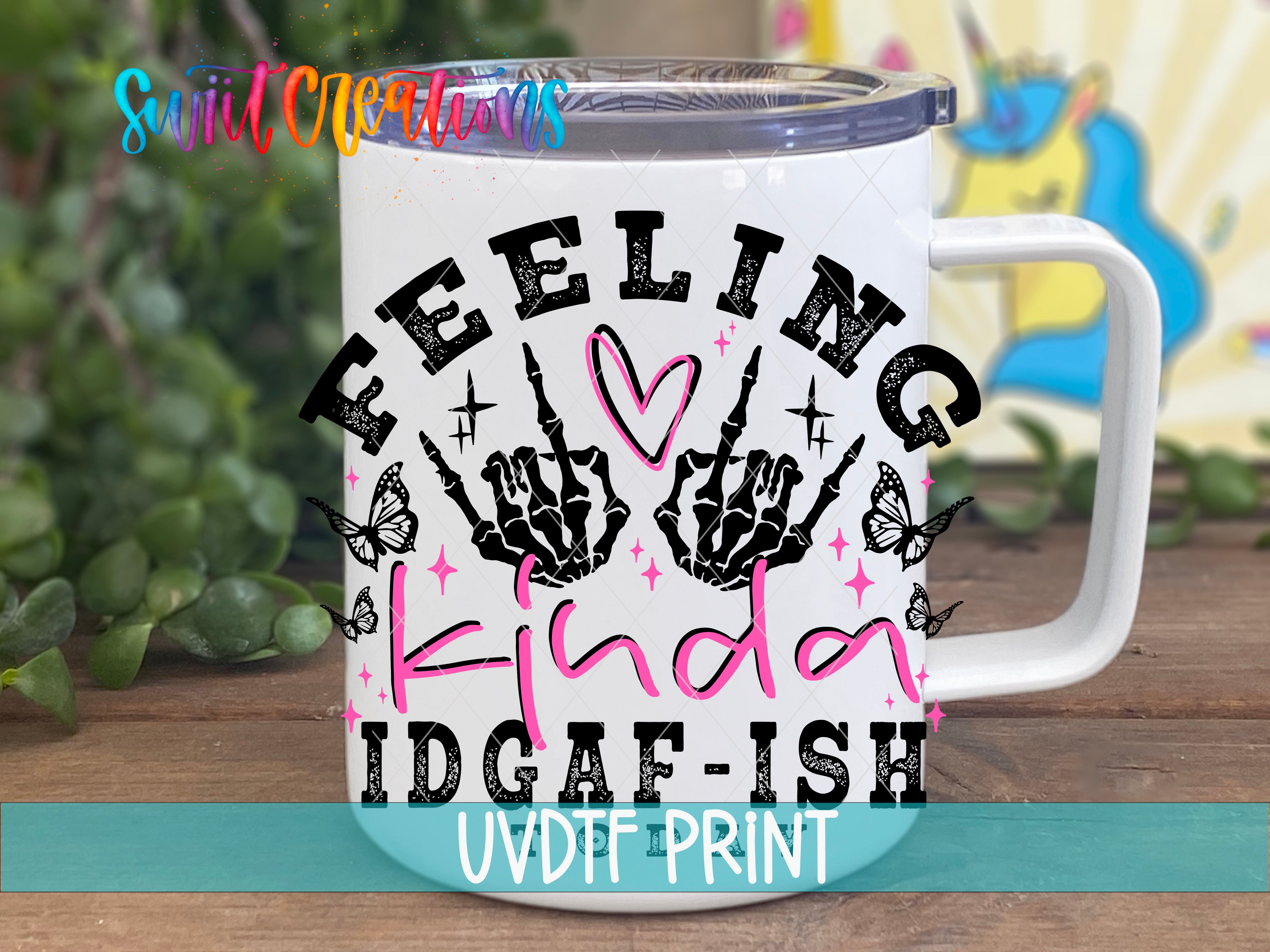 A white mug with a colorful graphic design featuring the text "Feeling Kinda Idgafish" and various decorative elements such as butterflies and skeletal hands.