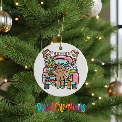 A white ceramic ornament hanging on a Christmas tree, featuring a gingerbread man sitting in a pink truck with a Christmas tree and ornaments.