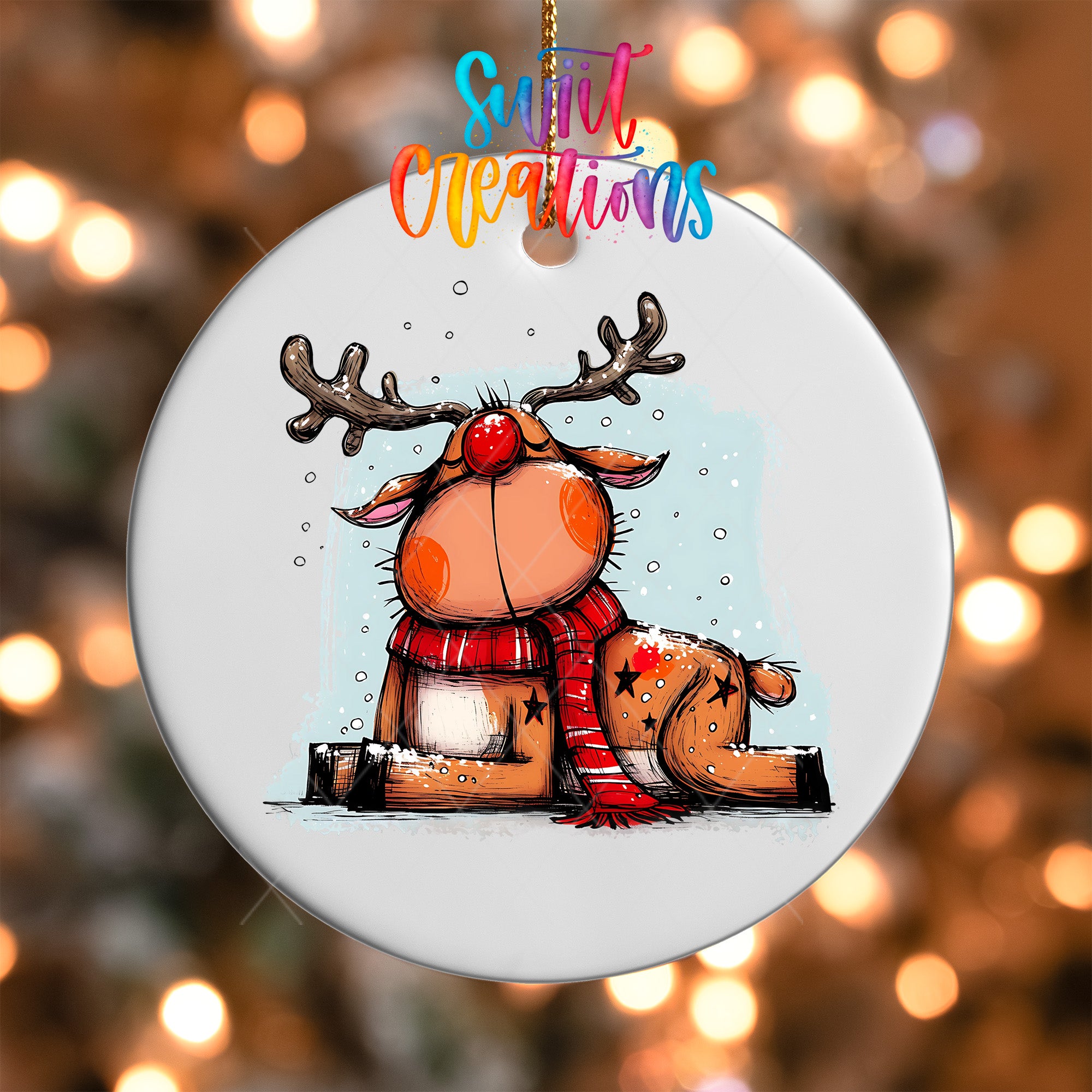 A white ornament featuring a cartoon reindeer with antlers and a red nose, wearing a red scarf, sitting on a snowy surface.