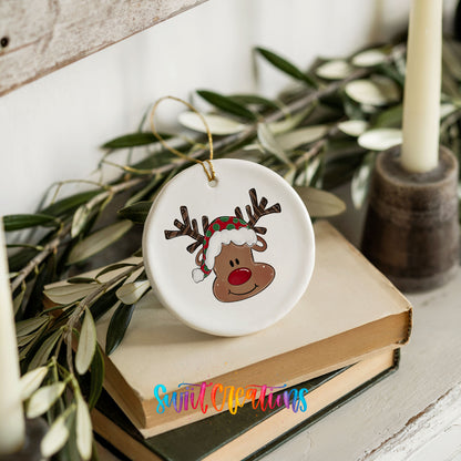 A white ceramic ornament with a reindeer face design is placed on top of a stack of books.