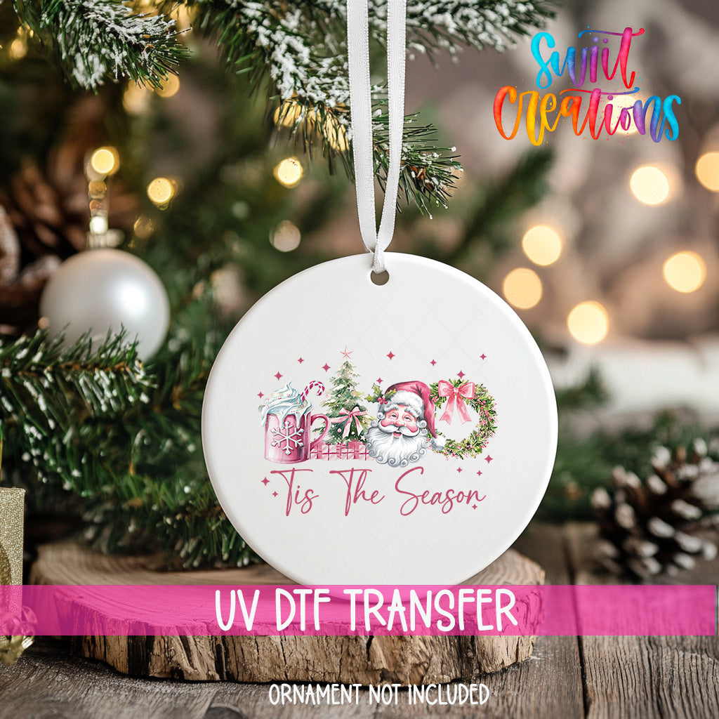 A white ceramic ornament with a Santa Claus and Christmas tree design hangs on a Christmas tree.