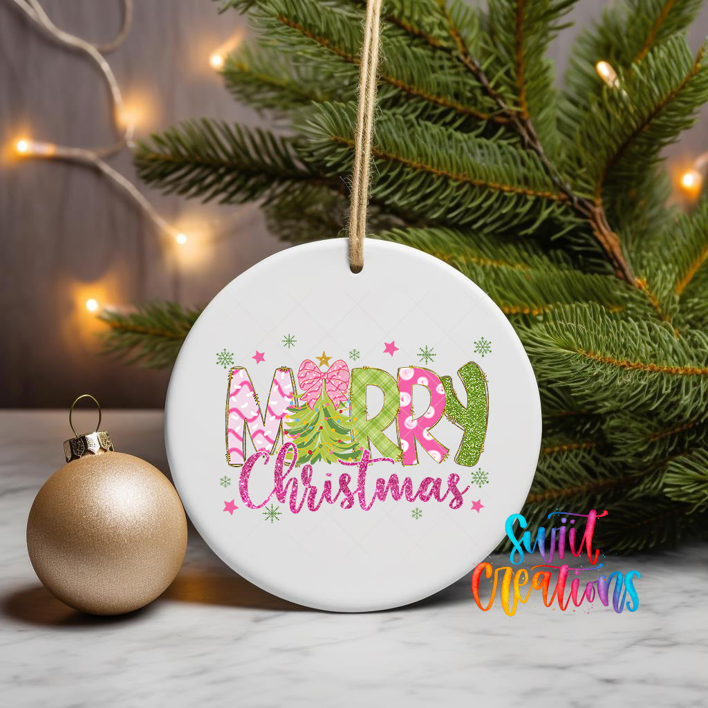 A white ceramic ornament with the text "Merry Christmas" in a colorful, festive font is displayed on a table, surrounded by a Christmas tree and twinkling lights.