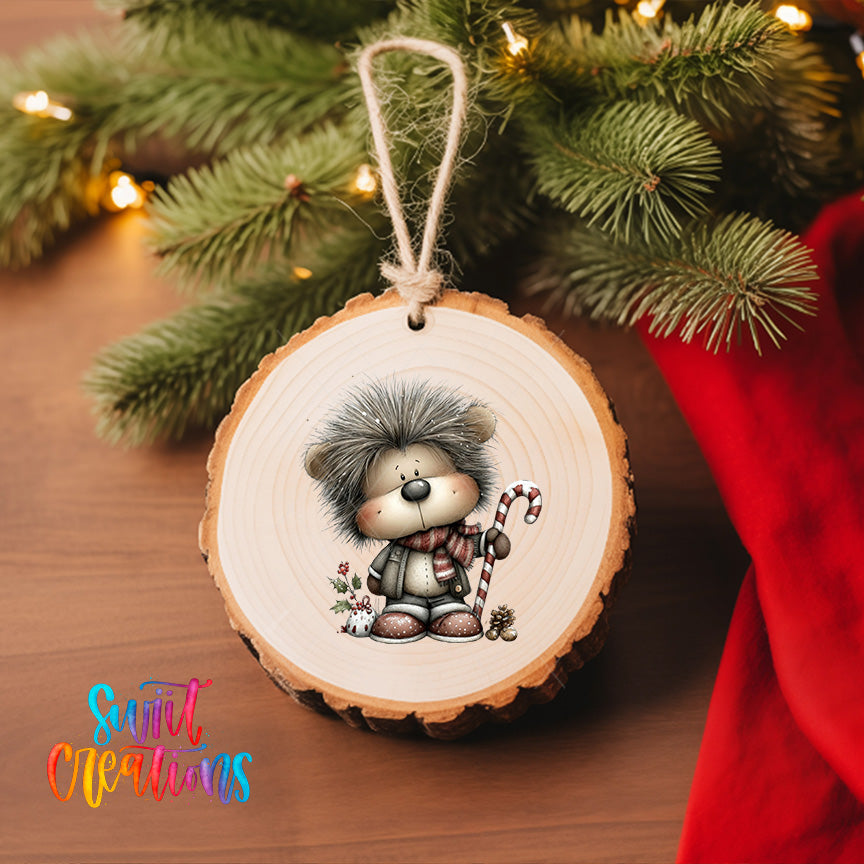 A wooden ornament featuring a cartoon hedgehog character is hanging on a Christmas tree, surrounded by pine branches and twinkling lights.