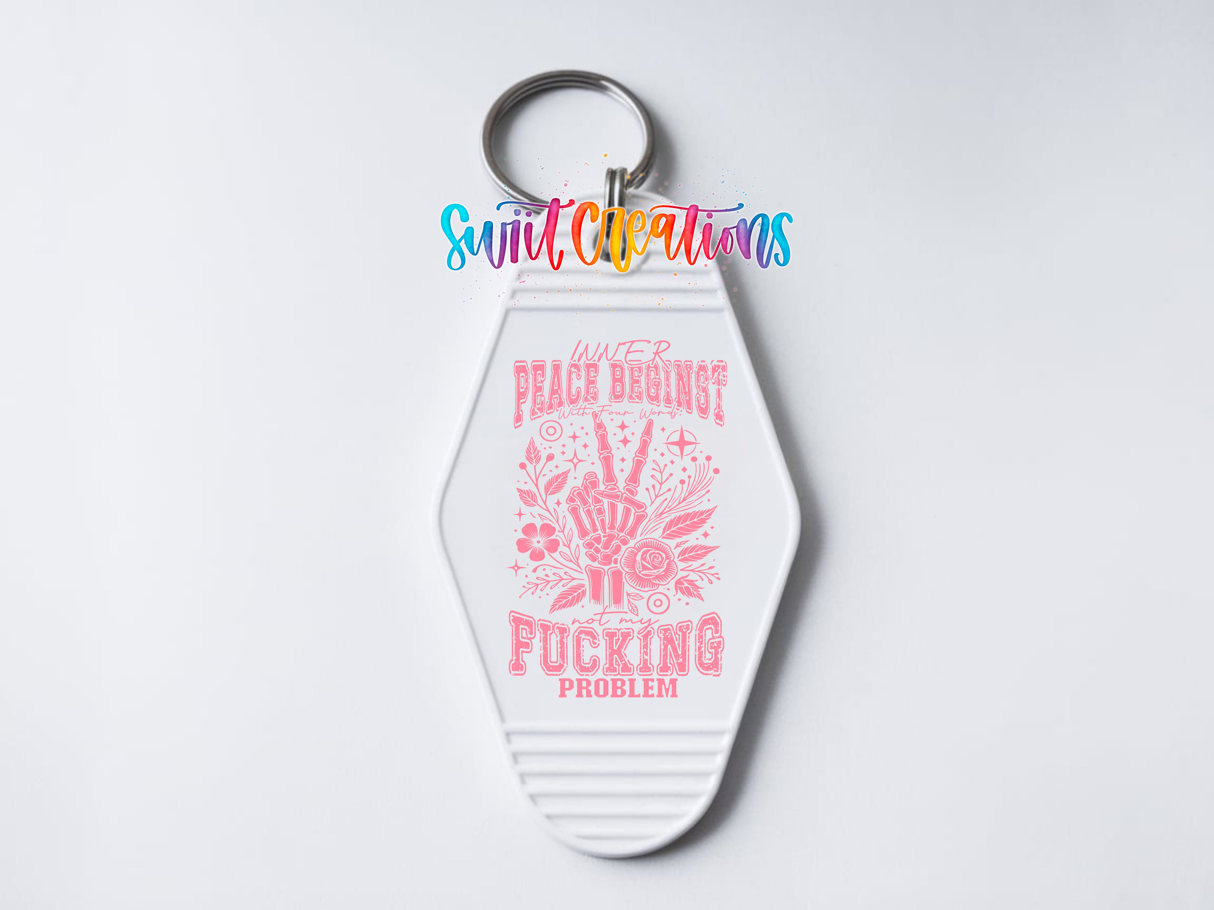 A keychain with a pink and white design featuring a hand gesture and text that reads "Peace begins with F*cking problem".
