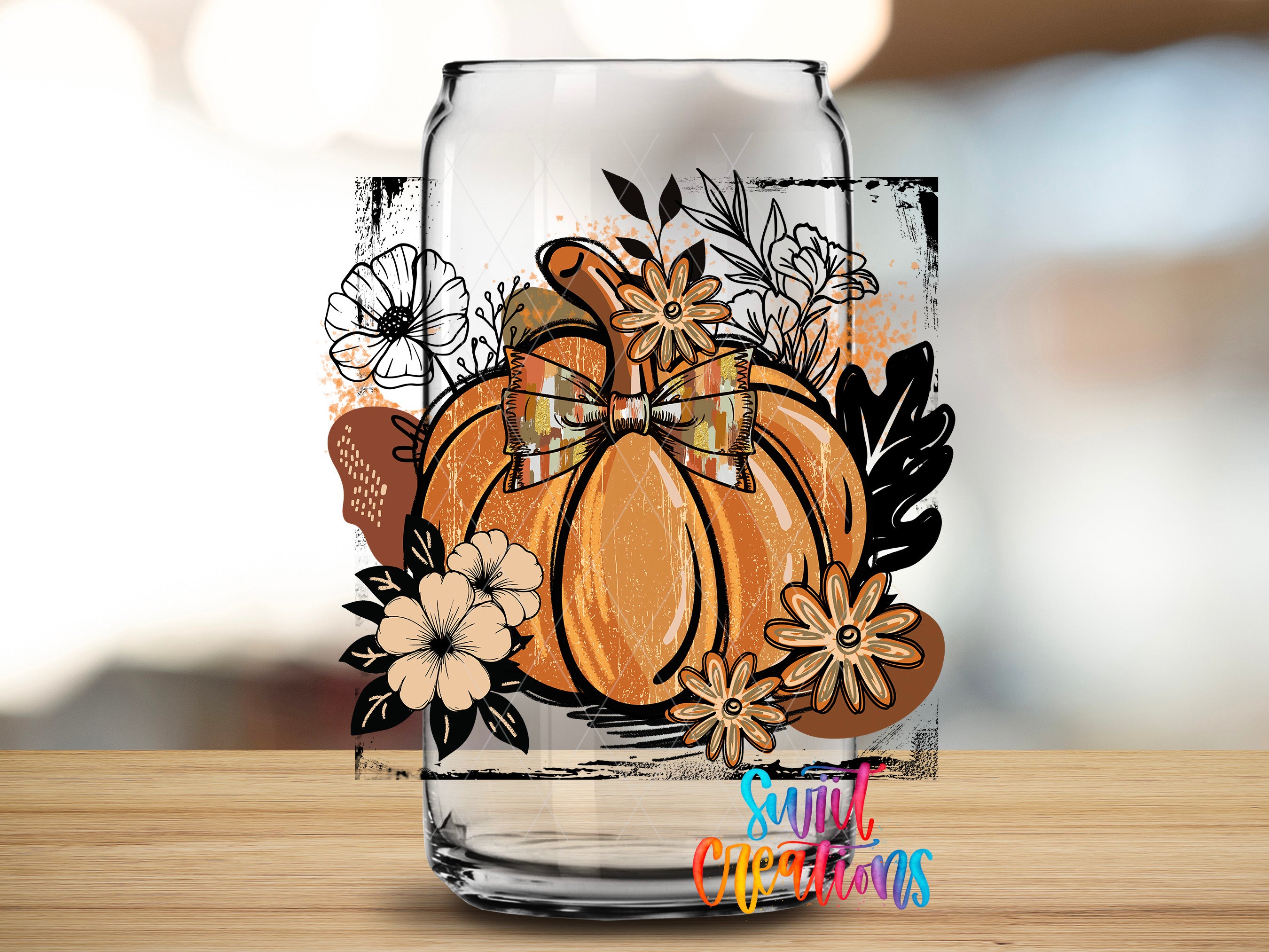 A glass jar with a pumpkin and floral design on it, placed on a wooden surface.