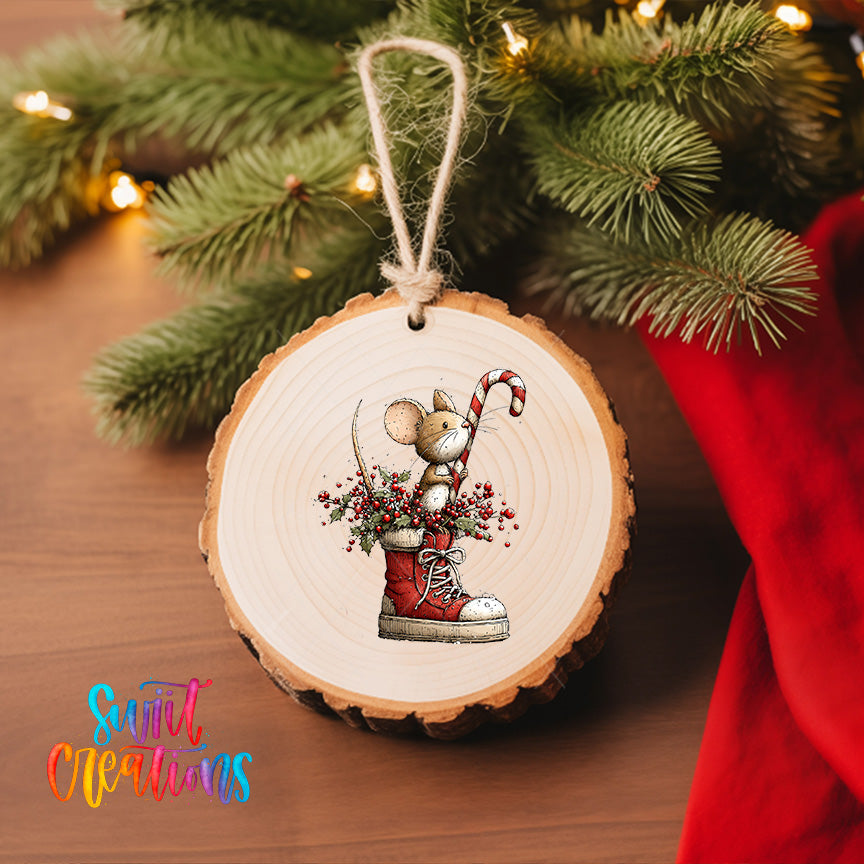 A wooden ornament featuring a mouse in a red shoe, holding a candy cane and berries, is hanging on a Christmas tree.