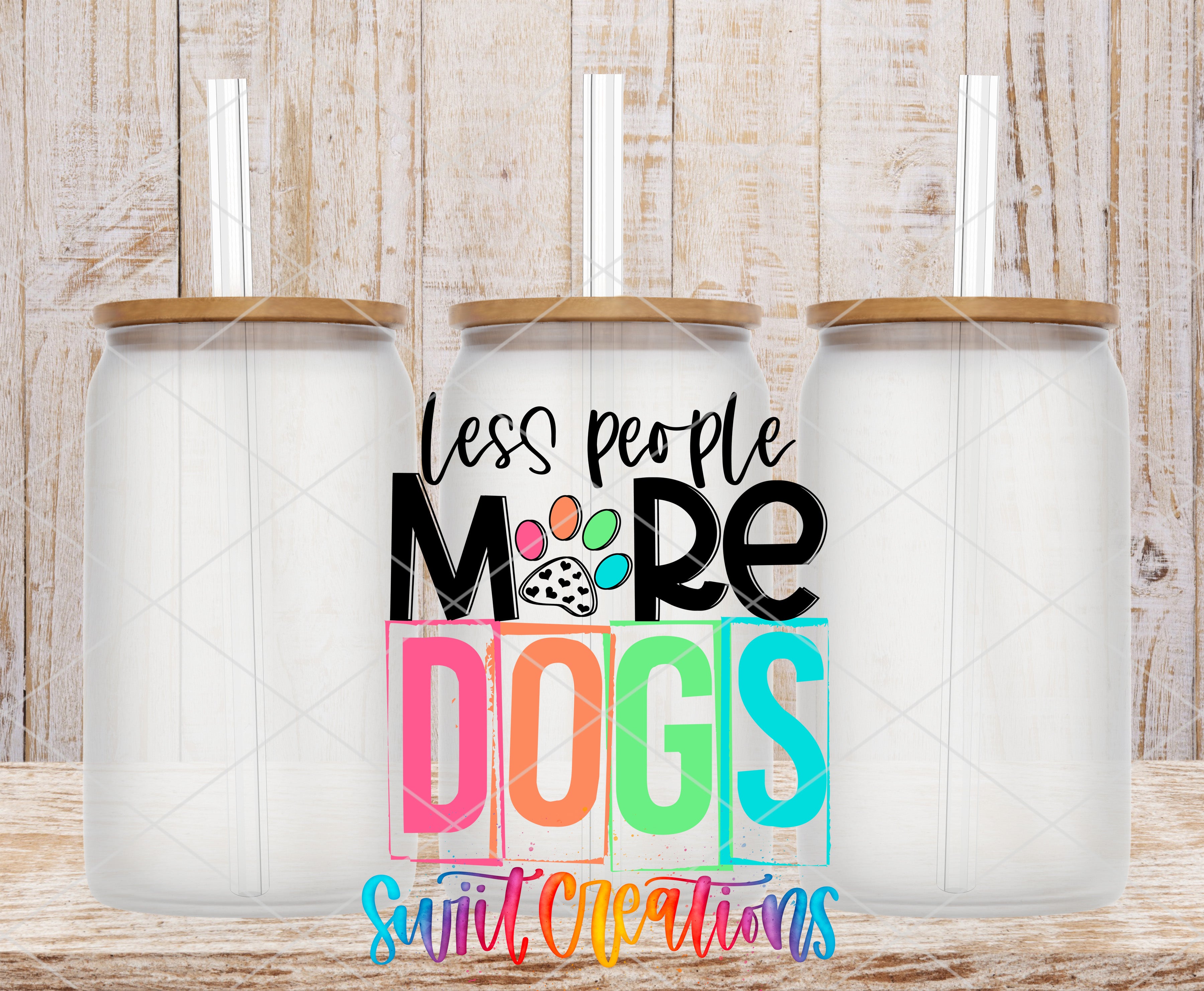 three glass jars with lids, arranged in a row against a wooden background. The jars have straws sticking out of the lids. The text "less people, more dogs" is displayed prominently in the center of the image, with the word "dogs" written in a colorful, stylized font.