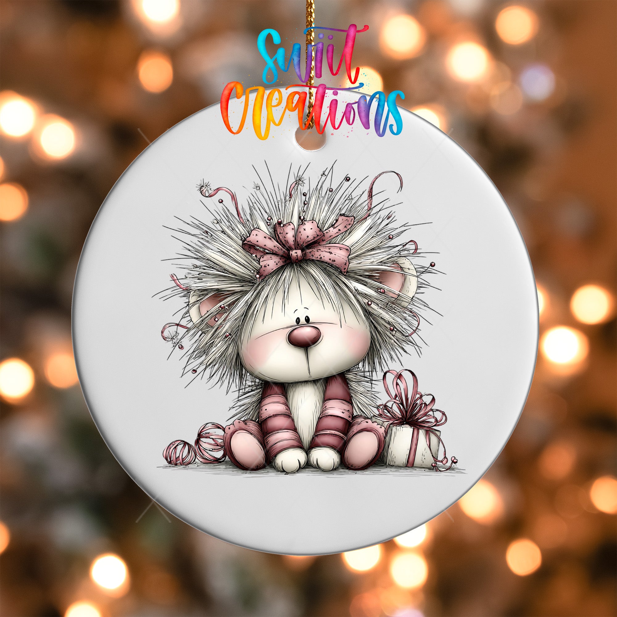 A white ornament with a cartoon illustration of a lion with a bow on its head, sitting on a gift box.