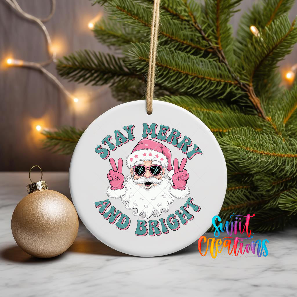 A white ceramic ornament with a Santa Claus image and the text "STAY MERRY AND BRIGHT" is displayed on a table, with a gold ornament and a Christmas tree in the background.
