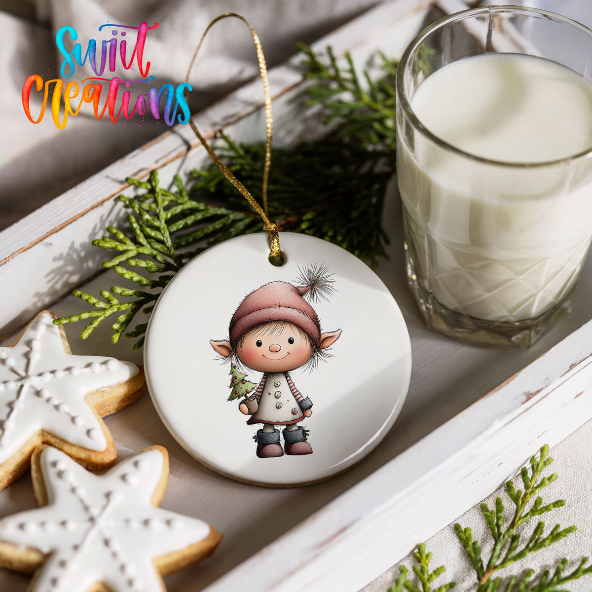 a Christmas ornament with a small elf on a white background, surrounded by cookies, a glass of milk, and greenery.