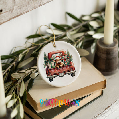 A ceramic ornament featuring a red truck with Christmas decorations and a dog is placed on top of a stack of books.