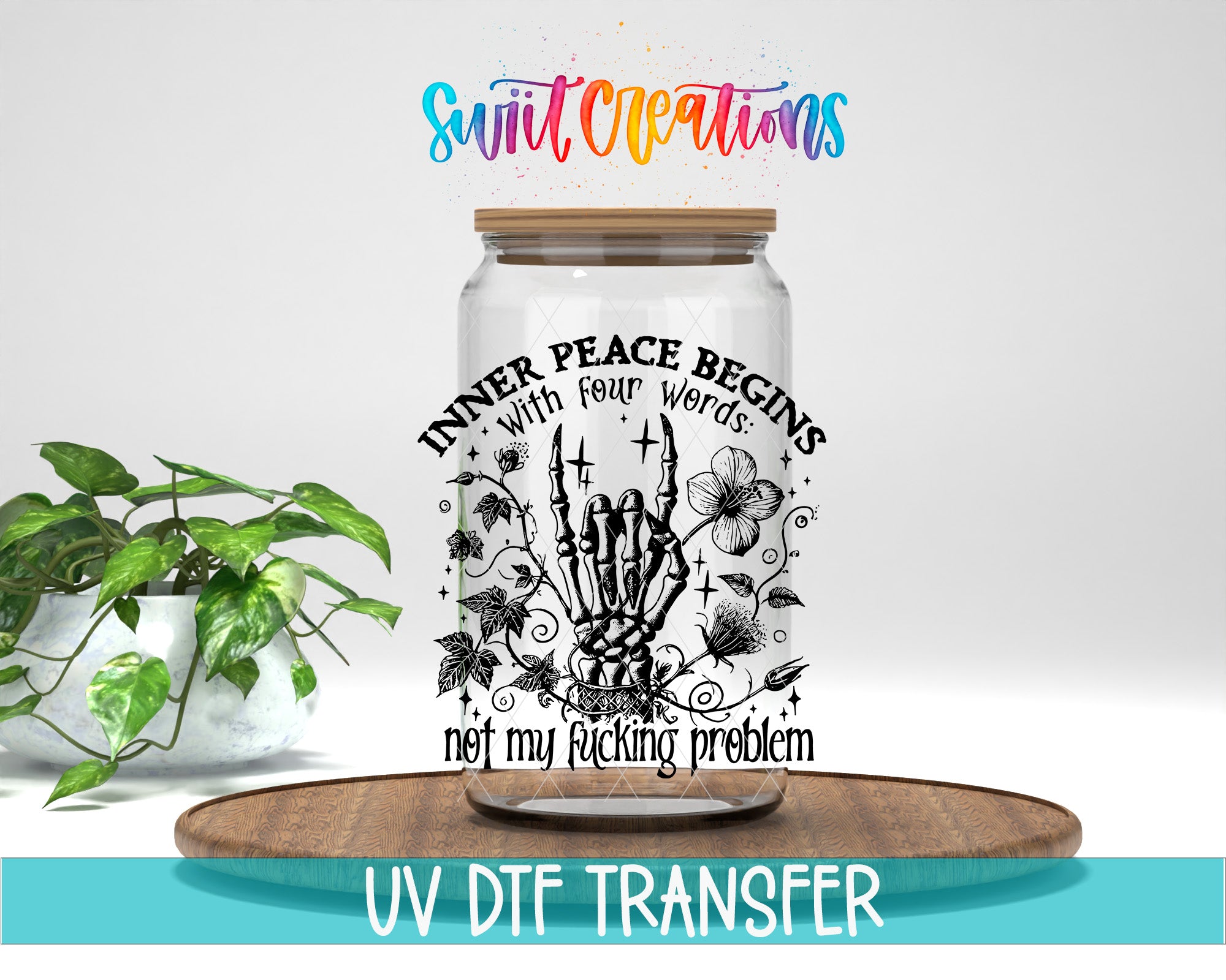 a glass jar with a label that says "INNER PEACE Begins with four weird words: not my fucking problem" and has a skeleton hand and floral design. The jar is placed on a wooden tray, and there is a potted plant in the background.