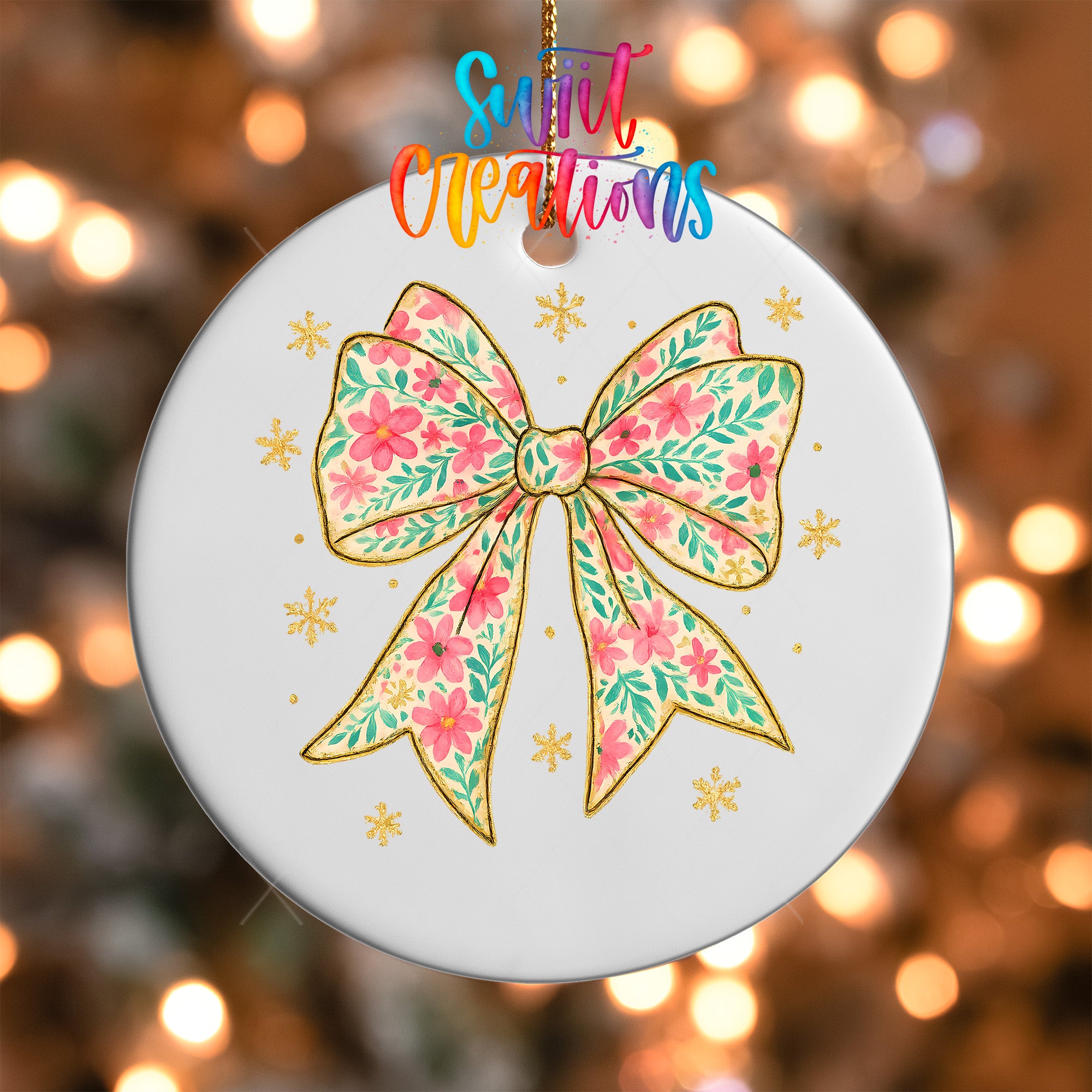 A white ceramic ornament with a floral bow design and snowflake decorations is hanging against a blurred background of lights.