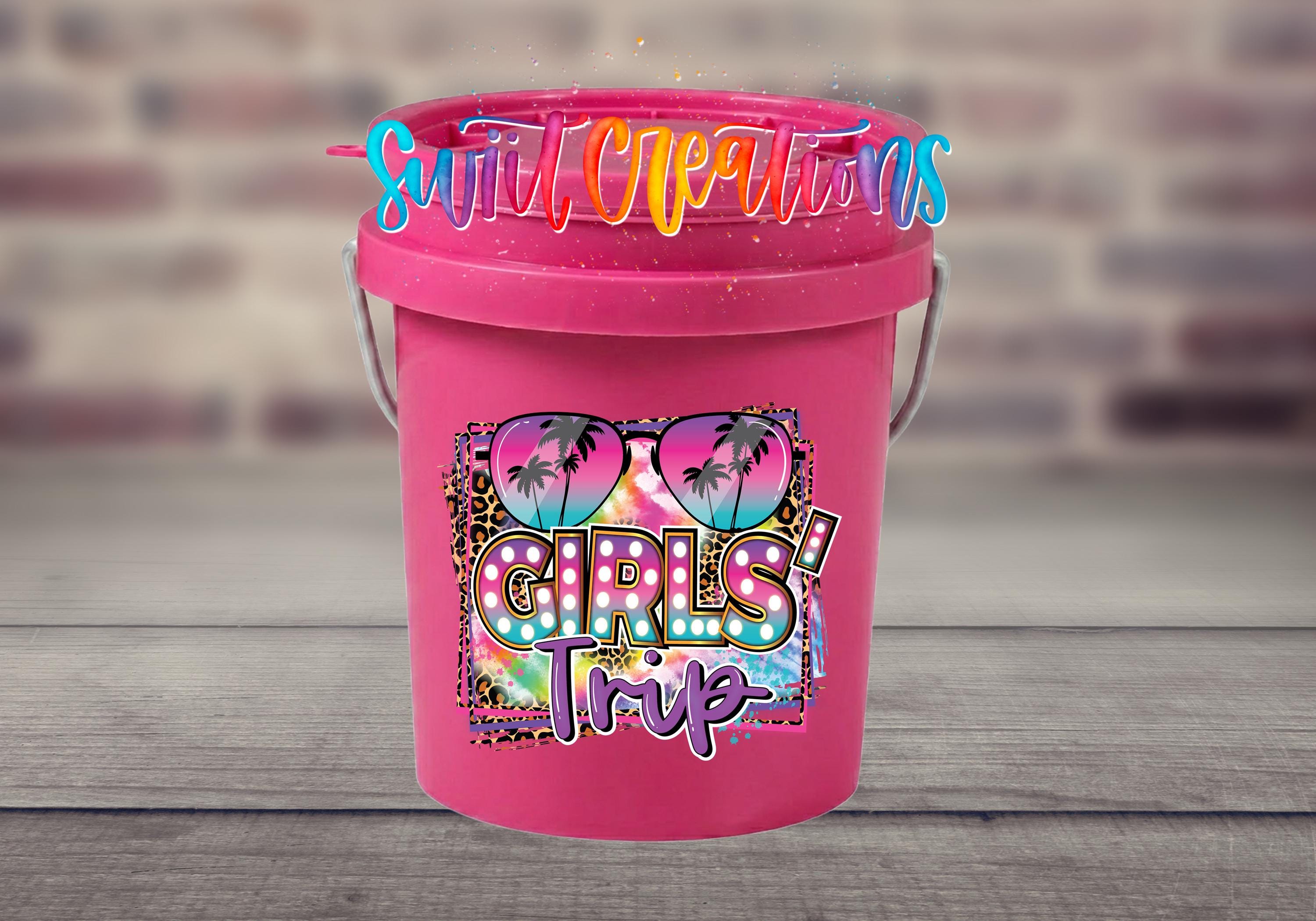 A pink bucket with a colorful graphic and text on it, placed on a wooden surface.