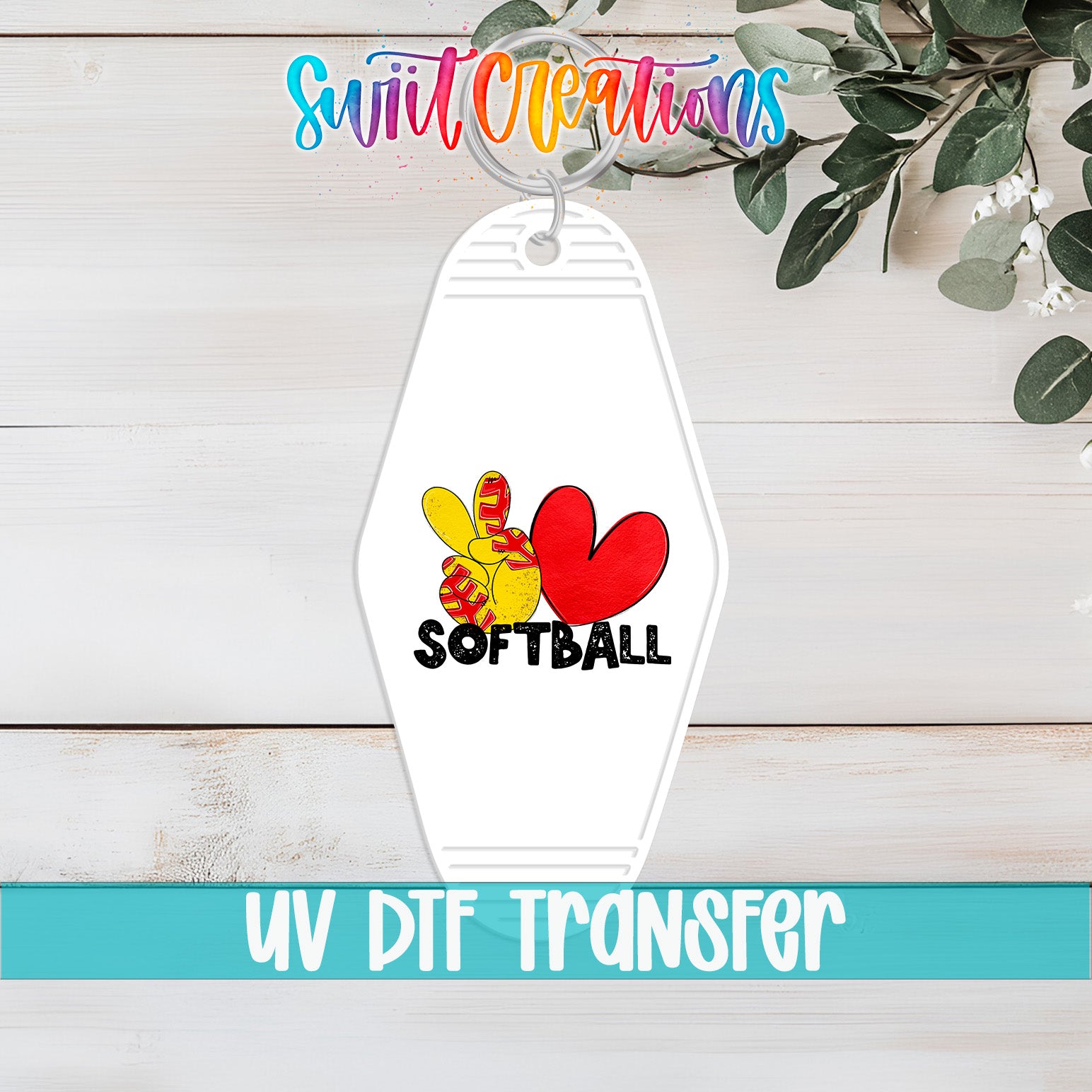 A keychain with a white hexagon shape and a colorful graphic design featuring a red heart, yellow and red flowers, and the word "SOFTBALL". The keychain is placed on a wooden surface, and there is a plant in the background.
