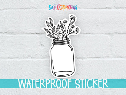 A sticker depicting a mason jar filled with flowers and leaves, placed on a white brick wall.