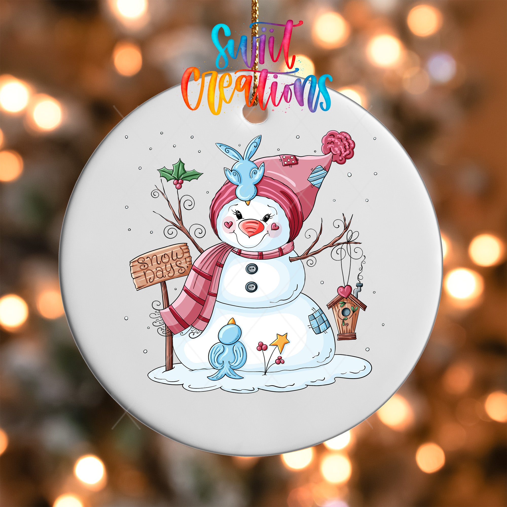 A snowman ornament with a sign that says "Snow Days" and various winter-themed elements, including a bird, a tree, and a snowman.