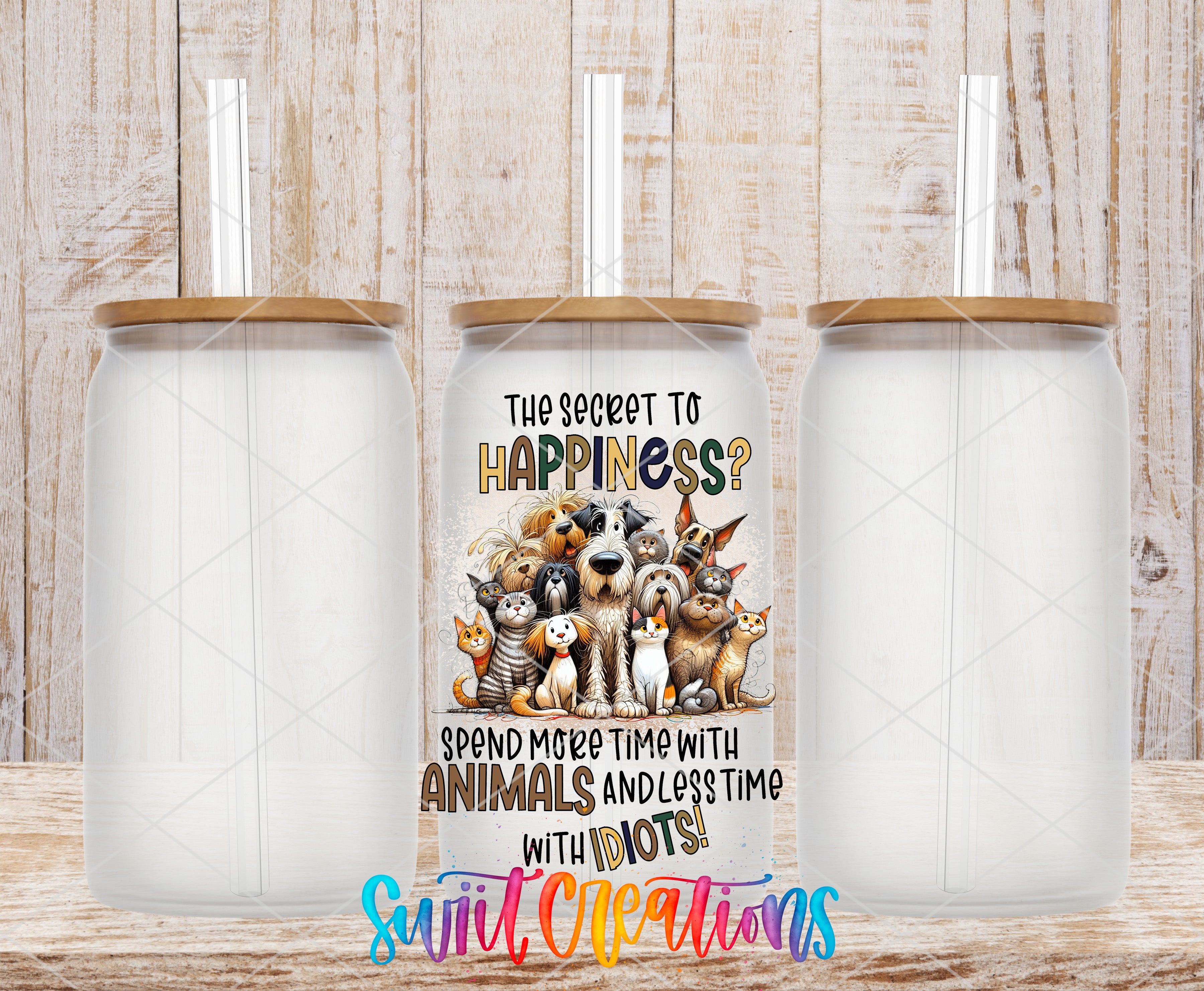 a trio of clear glass tumblers with straws, each containing a straw. The tumblers are set against a wooden background. The central focus of the image is a printed message on the tumbler that reads "The secret to happiness? Spend more time with animals and less time with idiots!"
