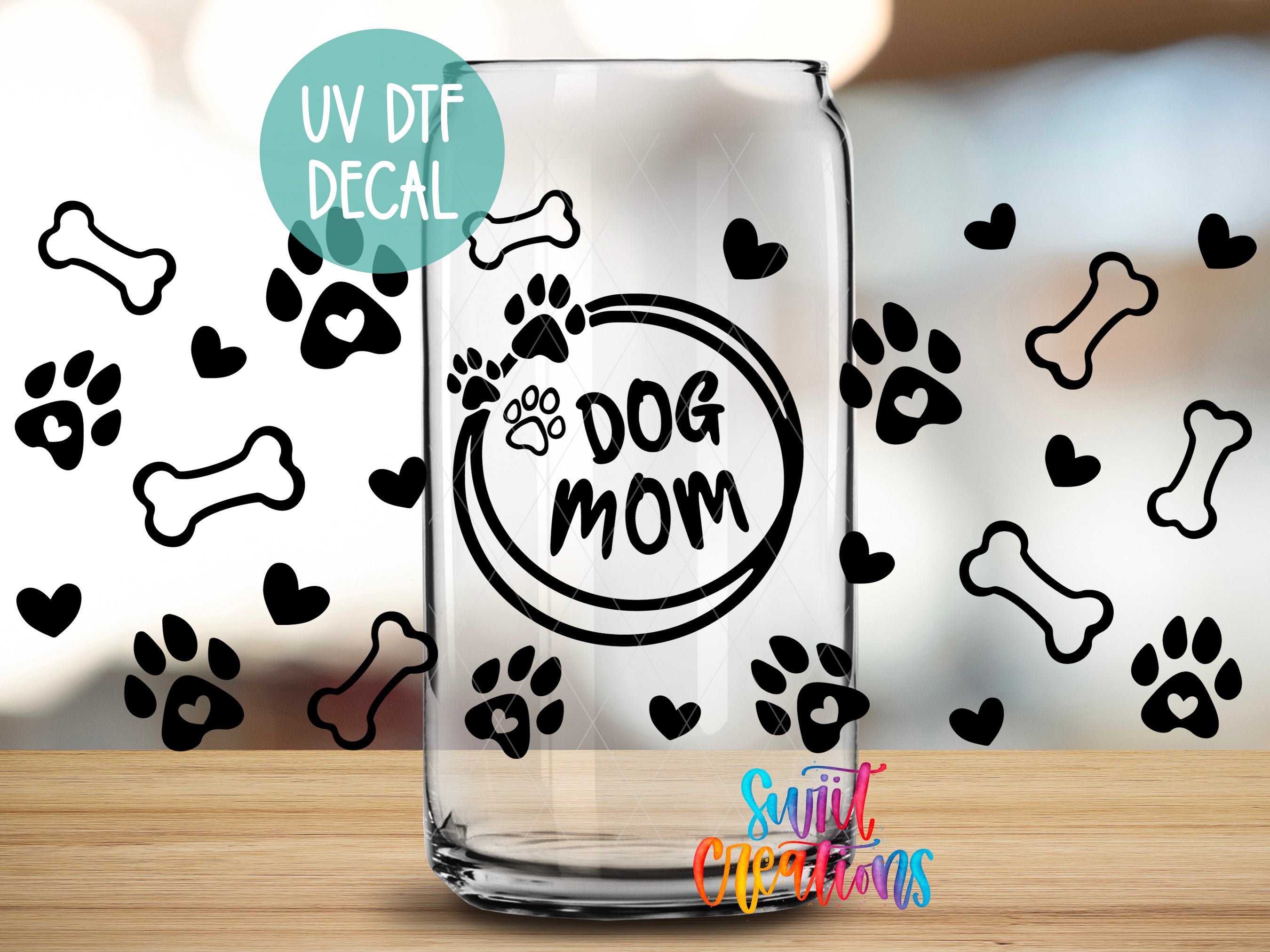 A glass can with a UV decal that says "DOG MOM" and various dog paw prints and bones surrounding it.