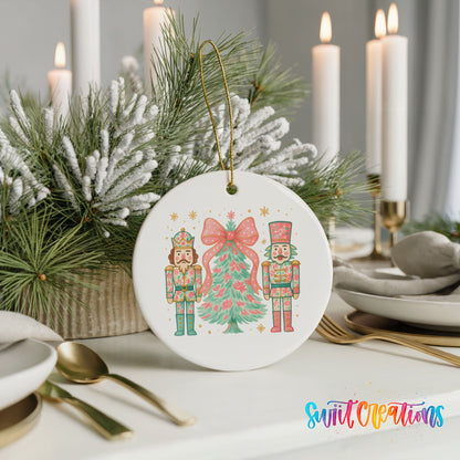 A white ornament featuring a nutcracker and a Christmas tree, with a bow on the nutcracker, is displayed on a table with candles and pine branches in the background.