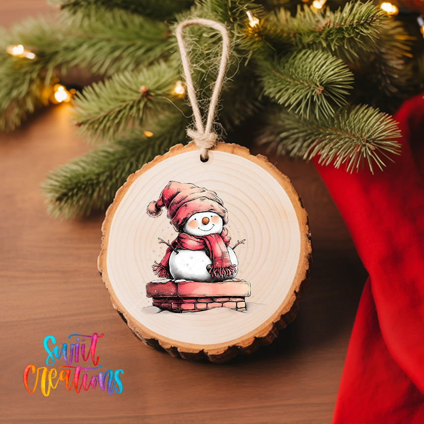 A wooden ornament featuring a snowman is hanging on a Christmas tree, surrounded by pine branches and twinkling lights.