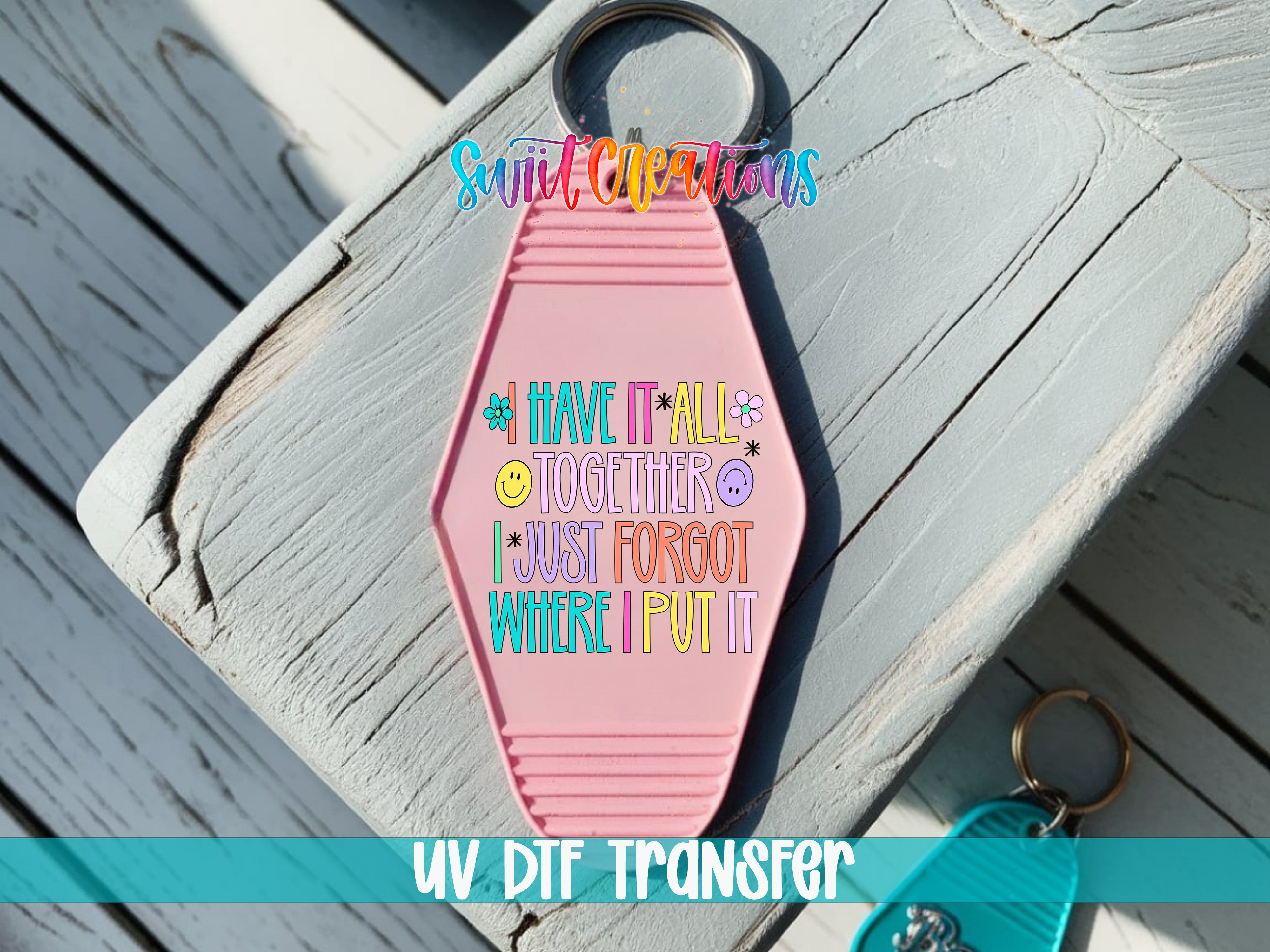 A pink keychain with a message printed on it, placed on a wooden surface.